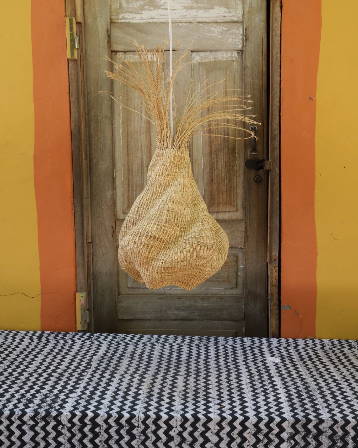 Woven lamp with a woven pattern on a wooden surface against a colorful background