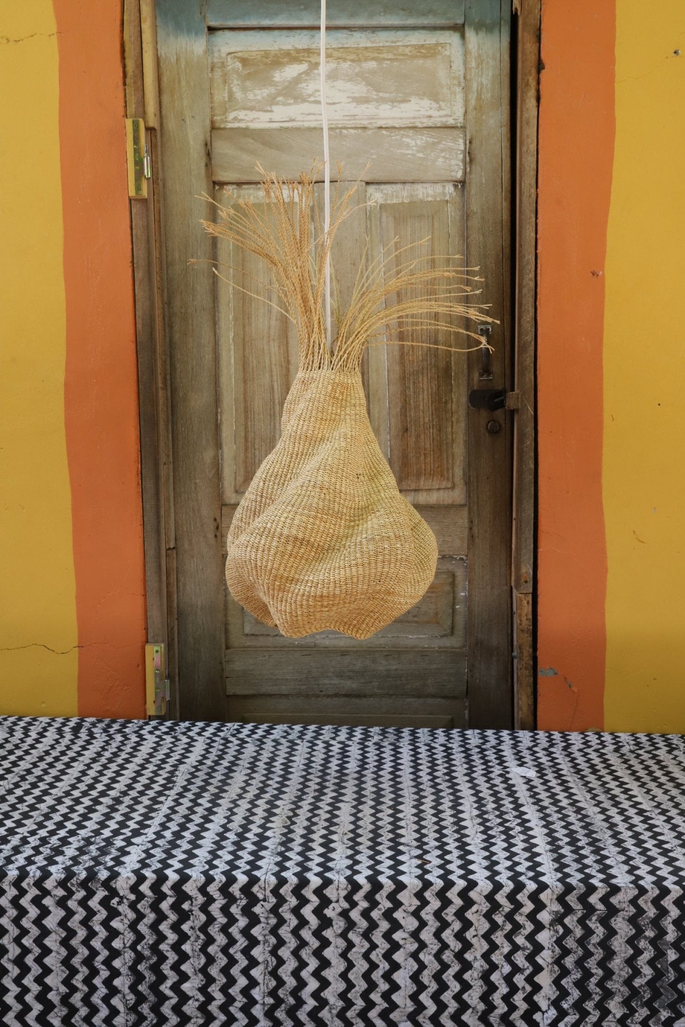 Woven lamp with a woven pattern on a wooden surface against a colorful background