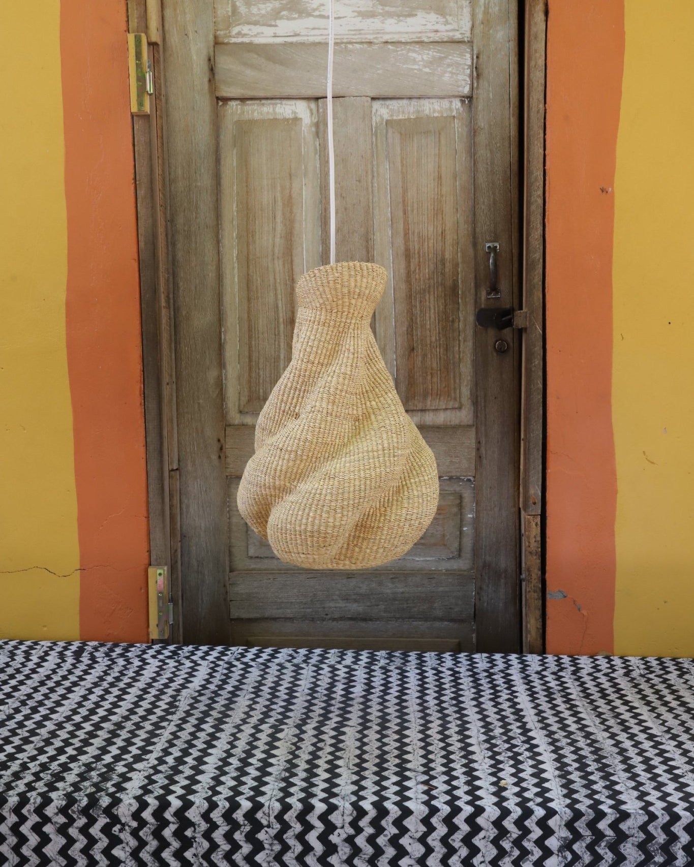 Woven lamp on a wooden surface with a colorful background