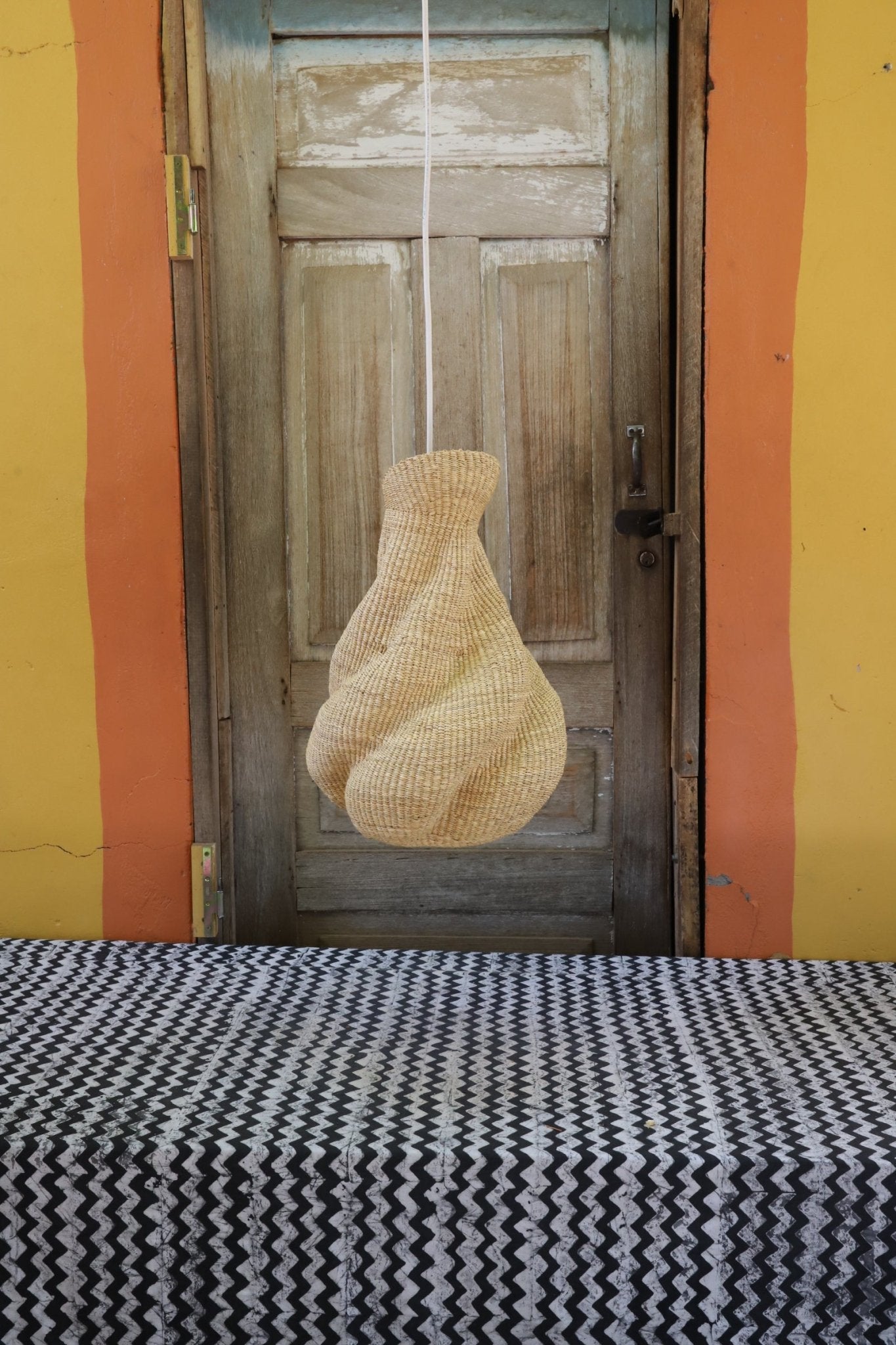 Woven lamp on a wooden surface with a colorful background