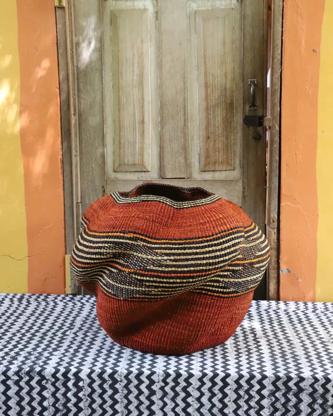 Colorful décor basket on a black and white cloth against a wooden door.