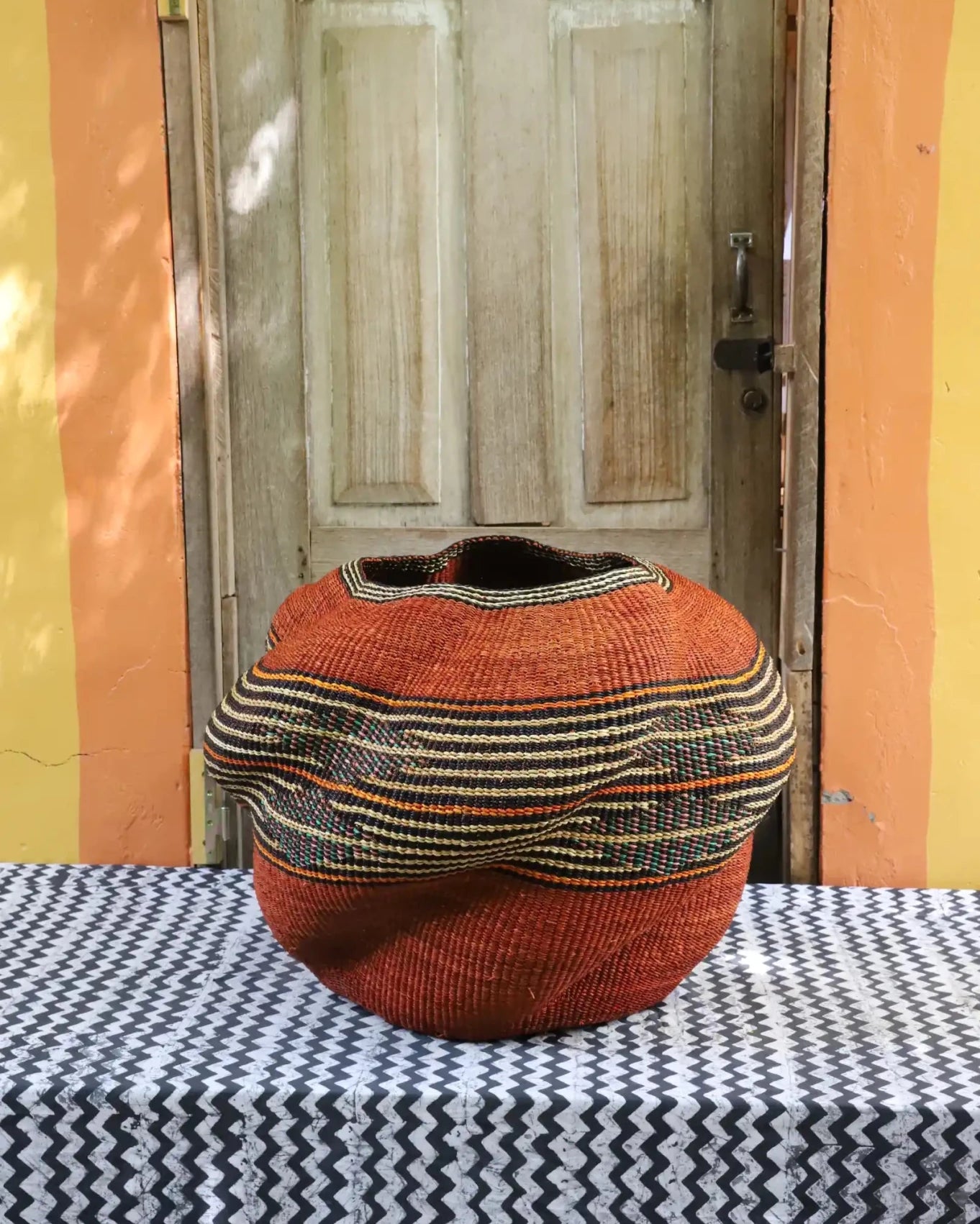 Colorful décor basket on a black and white cloth against a wooden door.