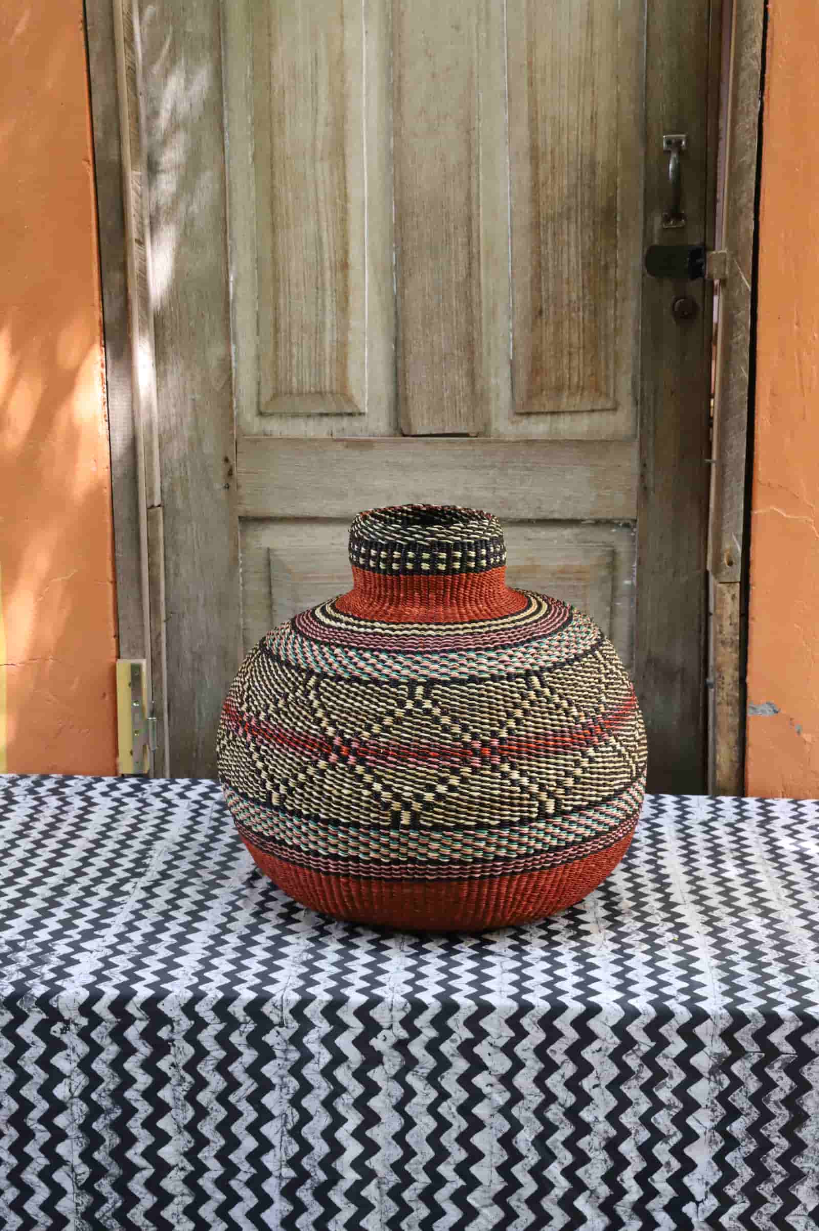 Beautiful basket with colorful patterns on a black and white cloth against a colorful background.