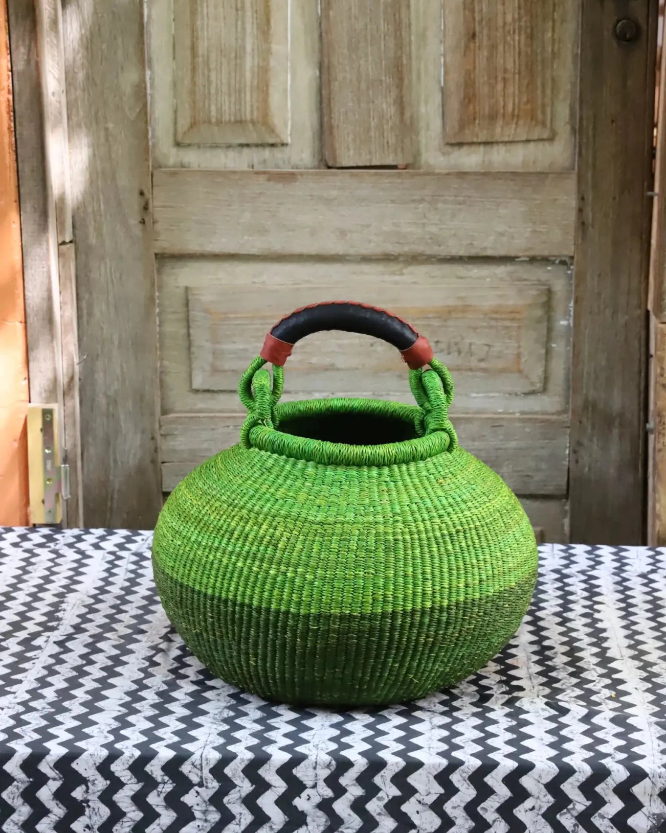 Colourful storage basket sitting on a black and white cloth against a wooden door.