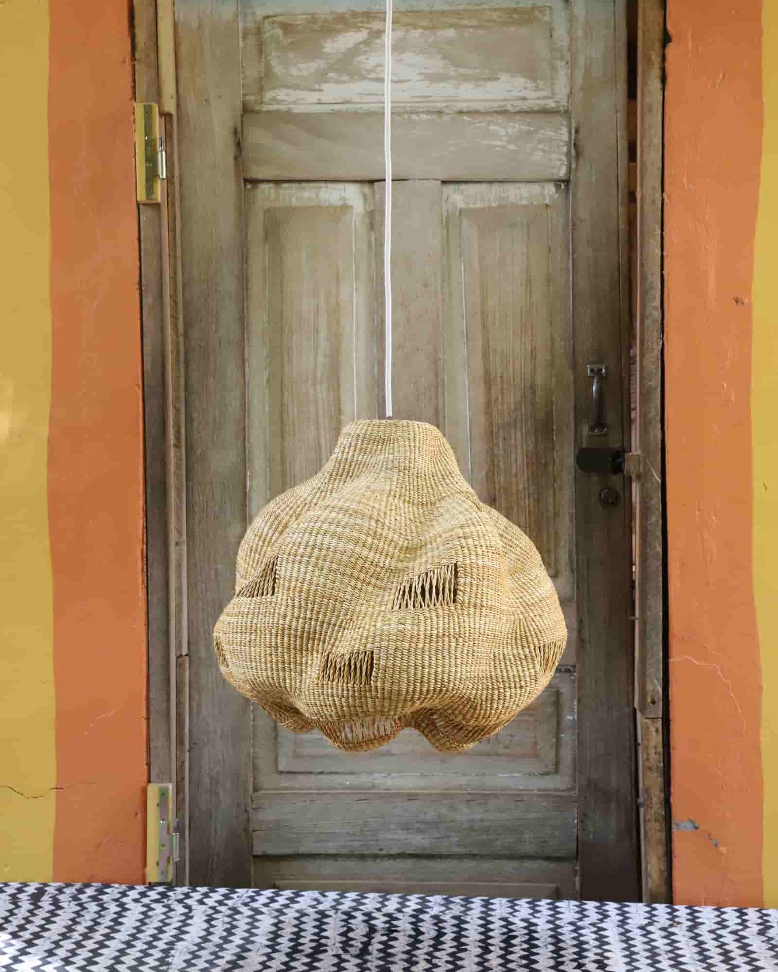 Woven basket hanging in front of a wooden door with a colorful wall background
