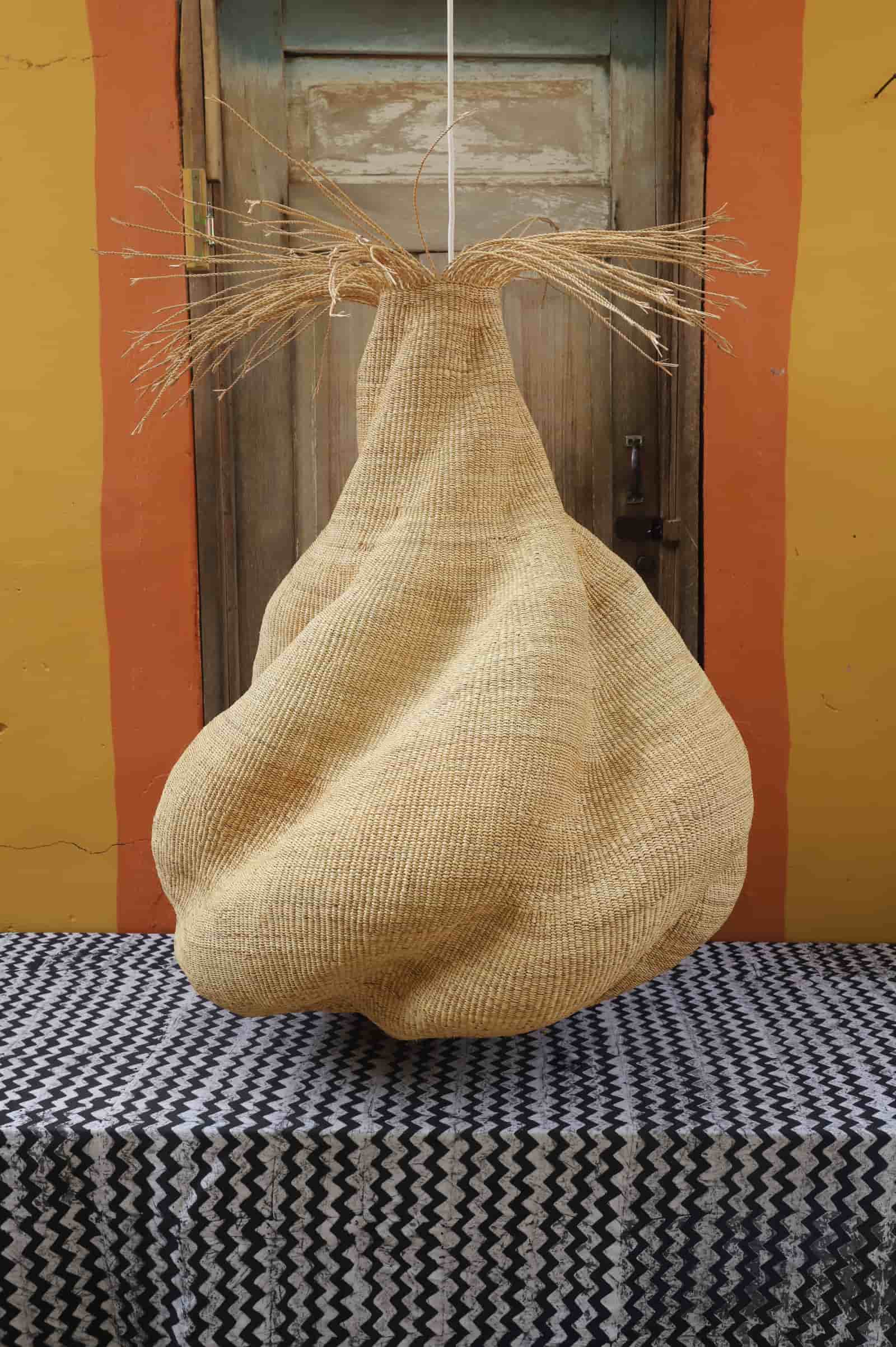 Woven basket hanging on a hook against a yellow wall with a black and white patterned tablecloth.