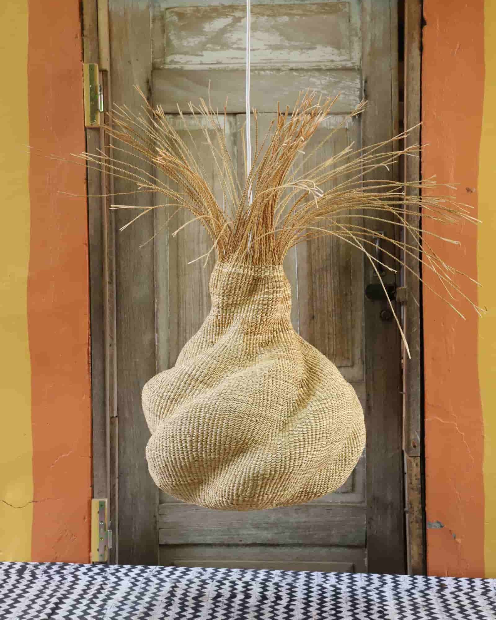 Decorative woven basket with straw-like material against a wooden door.