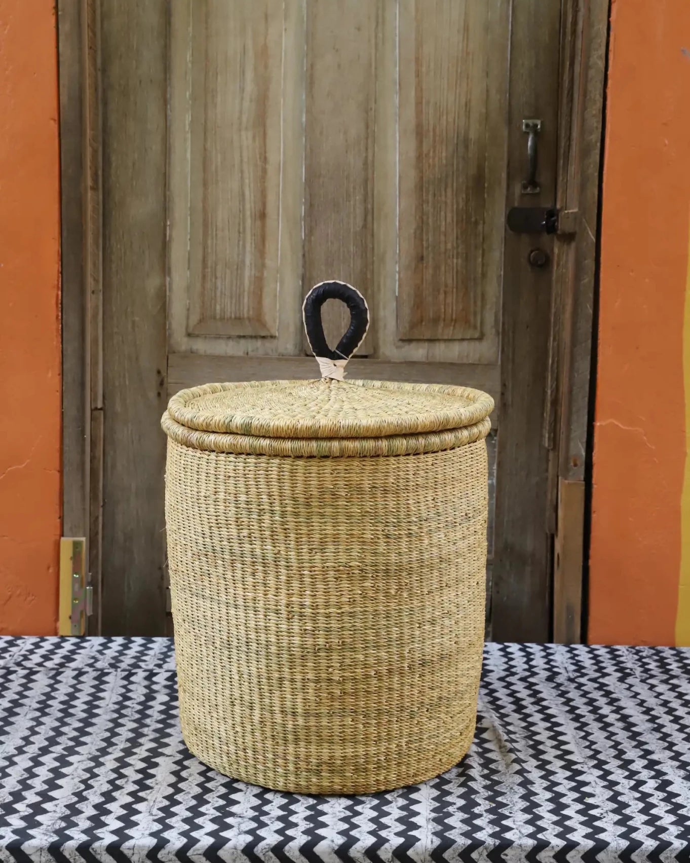 Lidded Laundry Basket with coil (Small) by The Baba Tree. Handwoven elephant grass with leather handle. Premium Bolgatanga artisan decor.