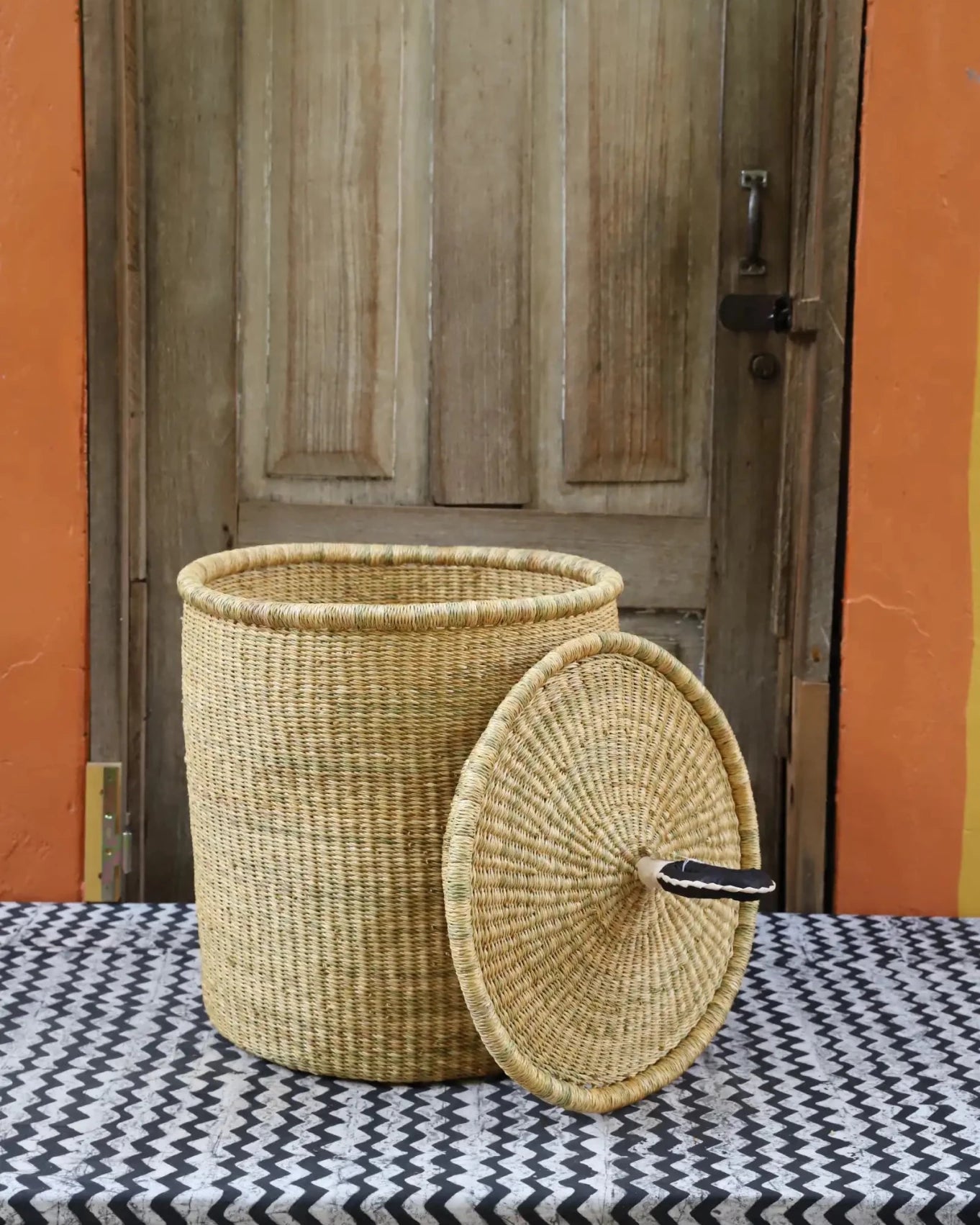 Lidded Laundry Basket with coil (Small) by The Baba Tree. Handwoven elephant grass with leather handle. Premium Bolgatanga artisan decor.