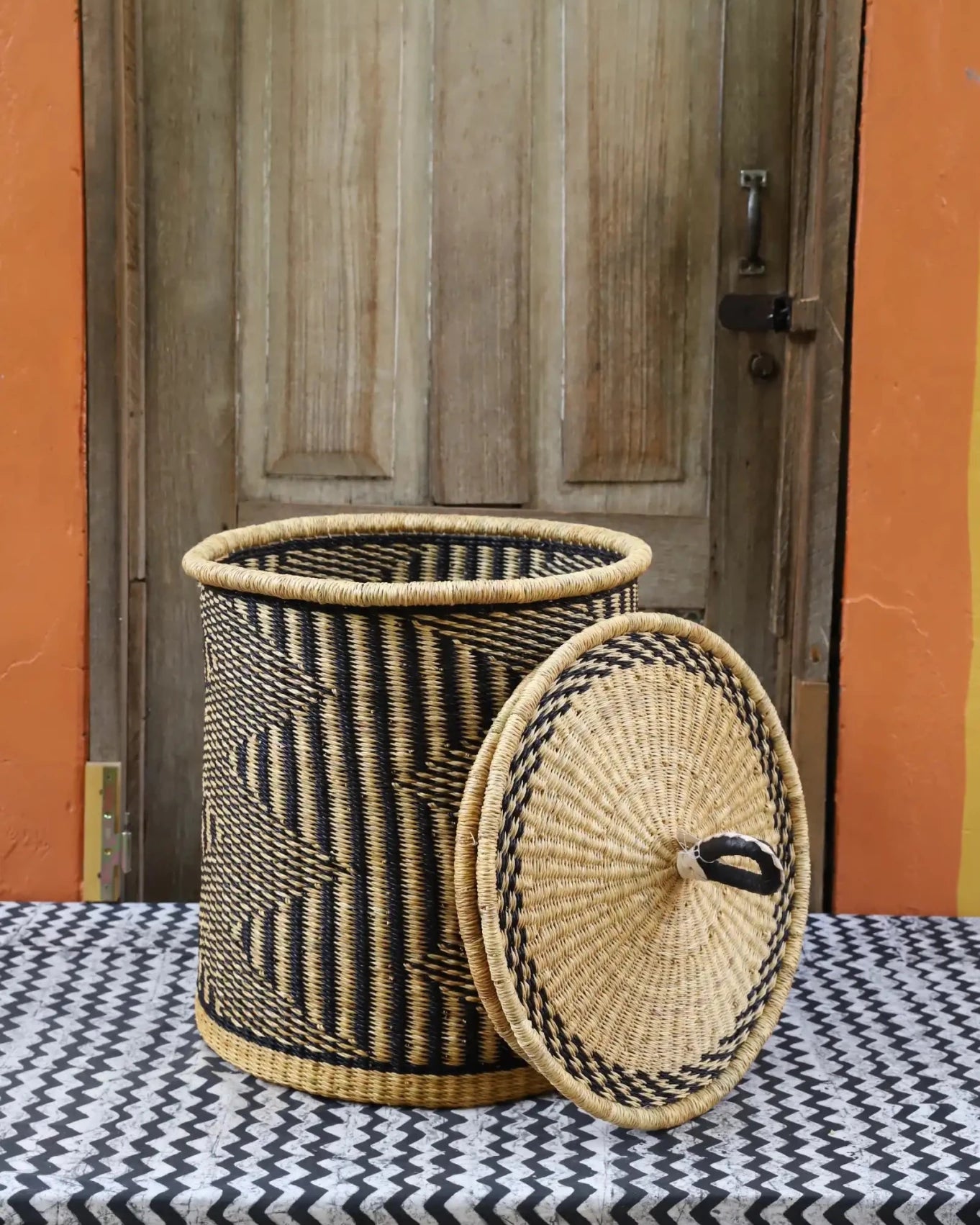 Lidded Laundry Basket with coil (Small) by The Baba Tree. Handwoven elephant grass with leather handle. Premium Bolgatanga artisan decor.