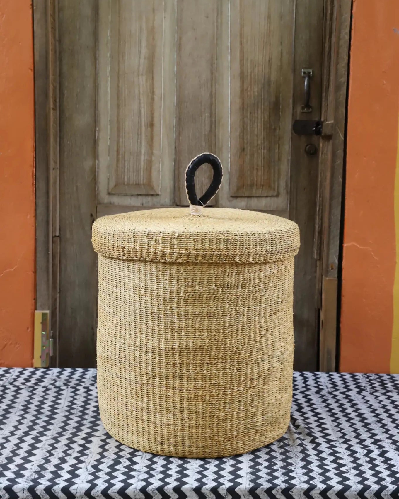 Lidded Laundry Basket (Medium) by The Baba Tree. Handwoven elephant grass with leather handle. Premium Bolgatanga artisan decor.