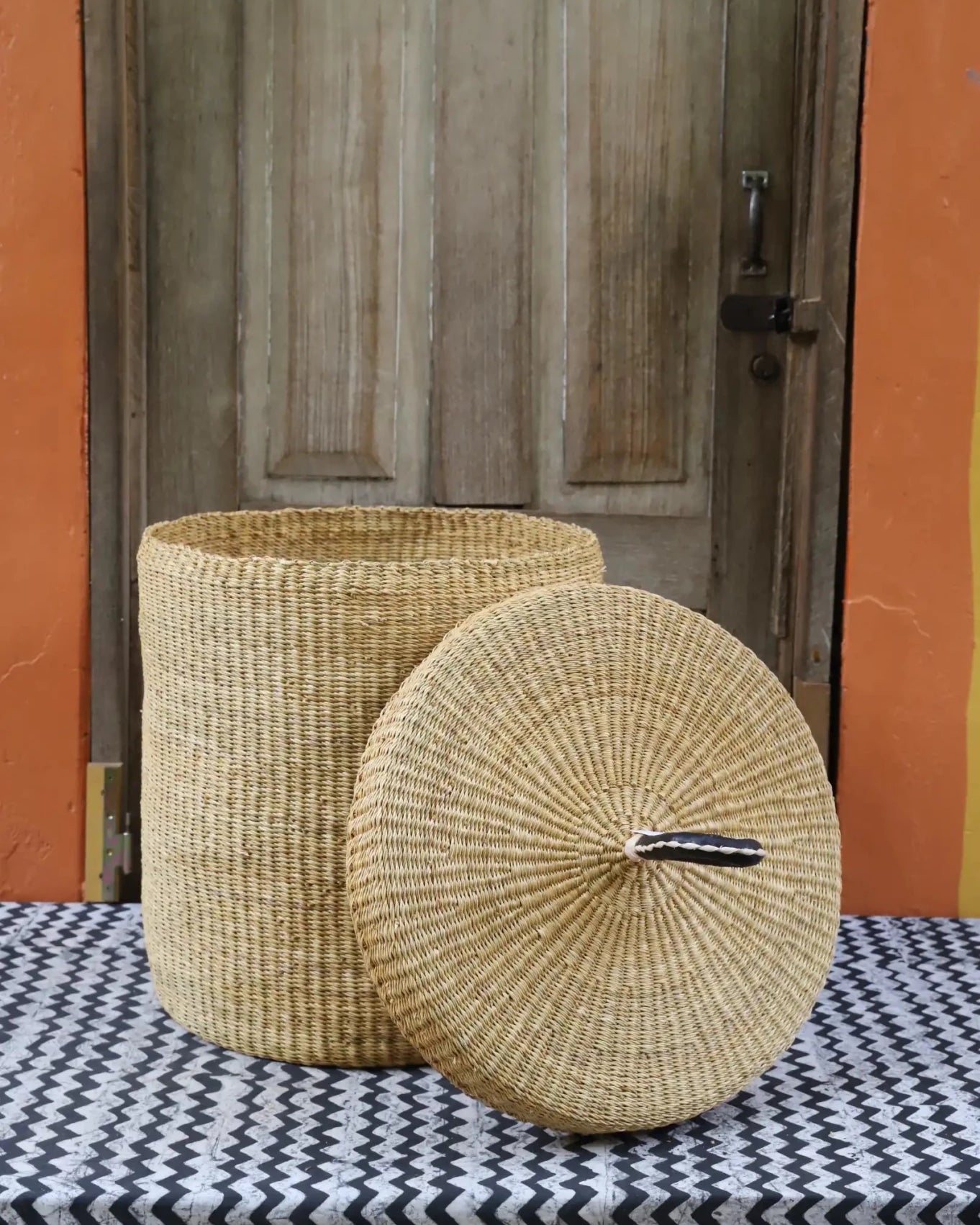 Lidded Laundry Basket (Medium) by The Baba Tree. Handwoven elephant grass with leather handle. Premium Bolgatanga artisan decor.