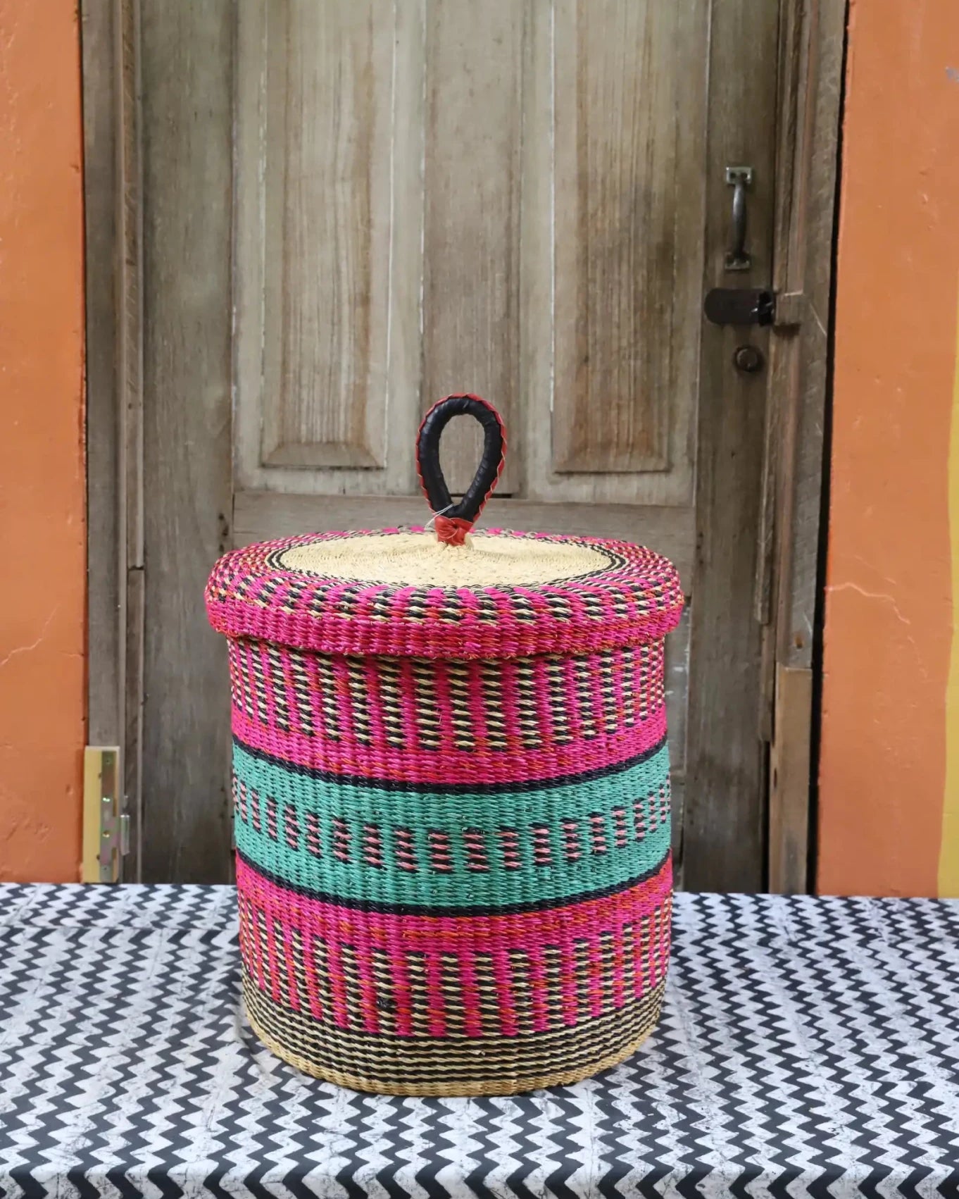 Lidded Laundry Basket (Small) by The Baba Tree. Handwoven elephant grass with leather handle. Premium Bolgatanga artisan decor.