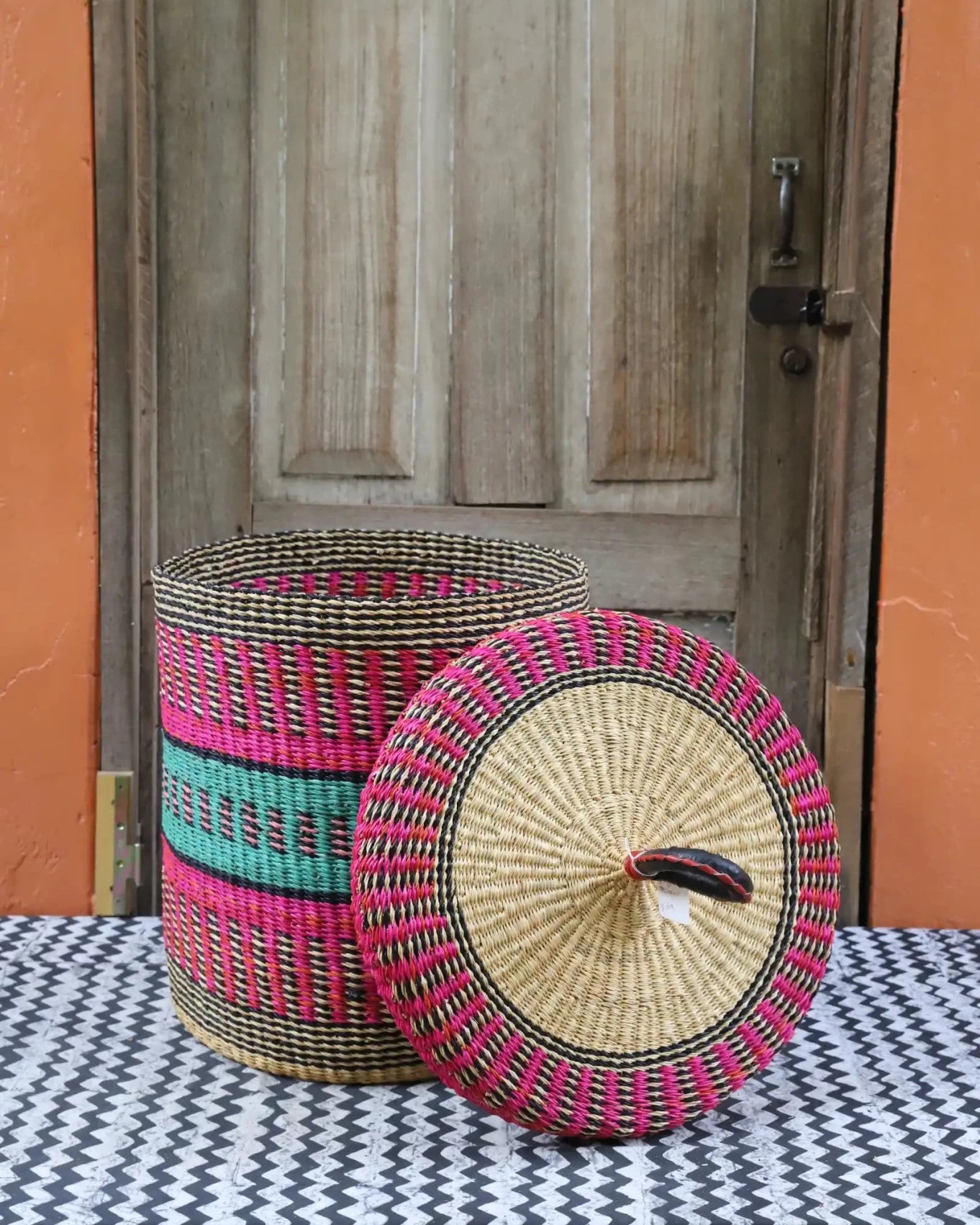 Lidded Laundry Basket (Small) by The Baba Tree. Handwoven elephant grass with leather handle. Premium Bolgatanga artisan decor.