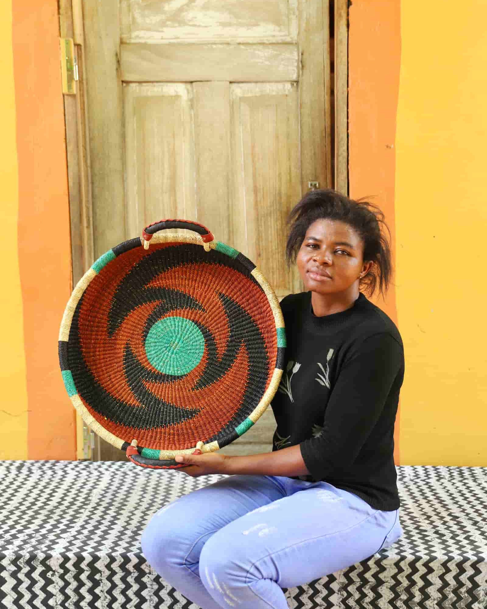 Person holding a woven basket against a colorful wall.