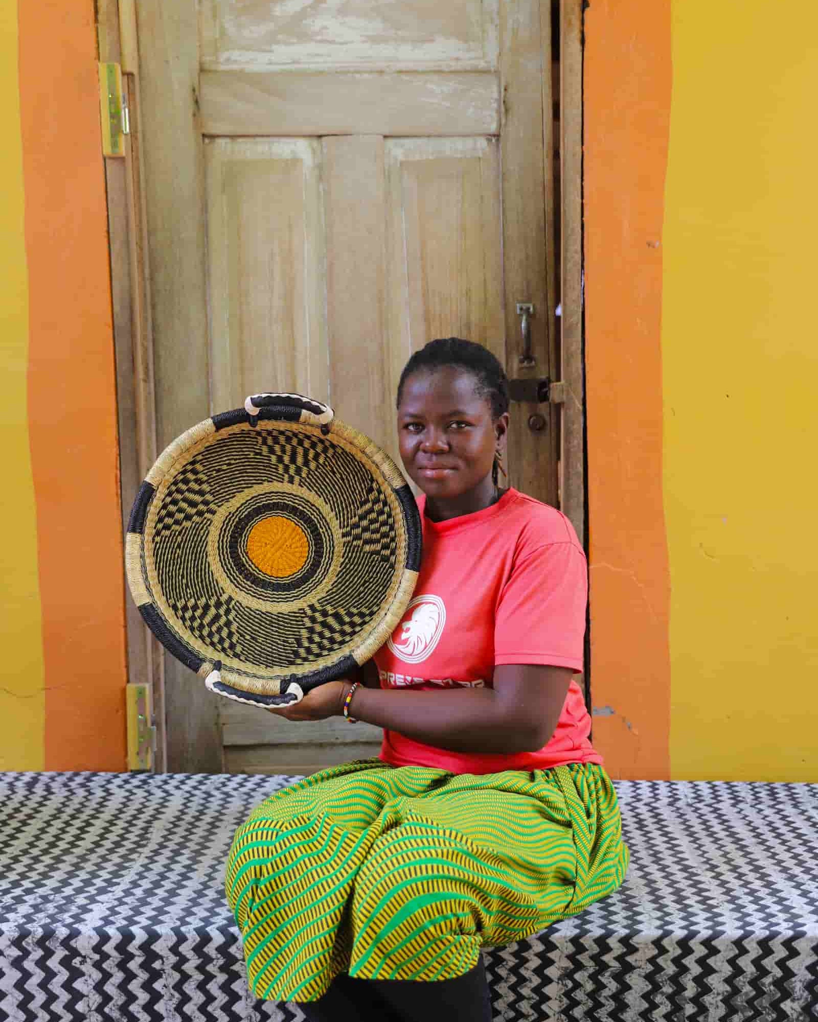 Woman holding a woven basket in front of a colorful wall with a wooden door.