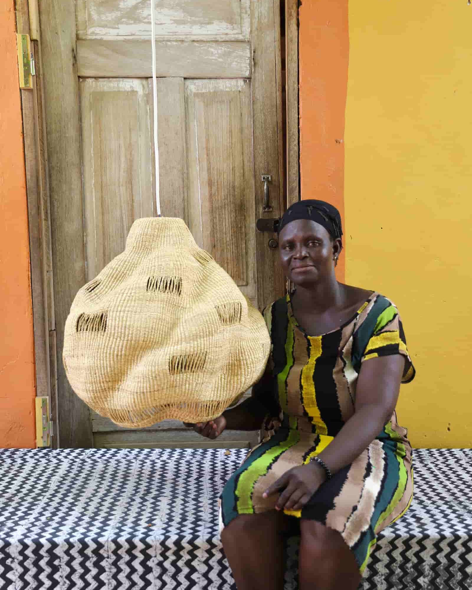Woman holding a woven basket in front of a colorful wall.