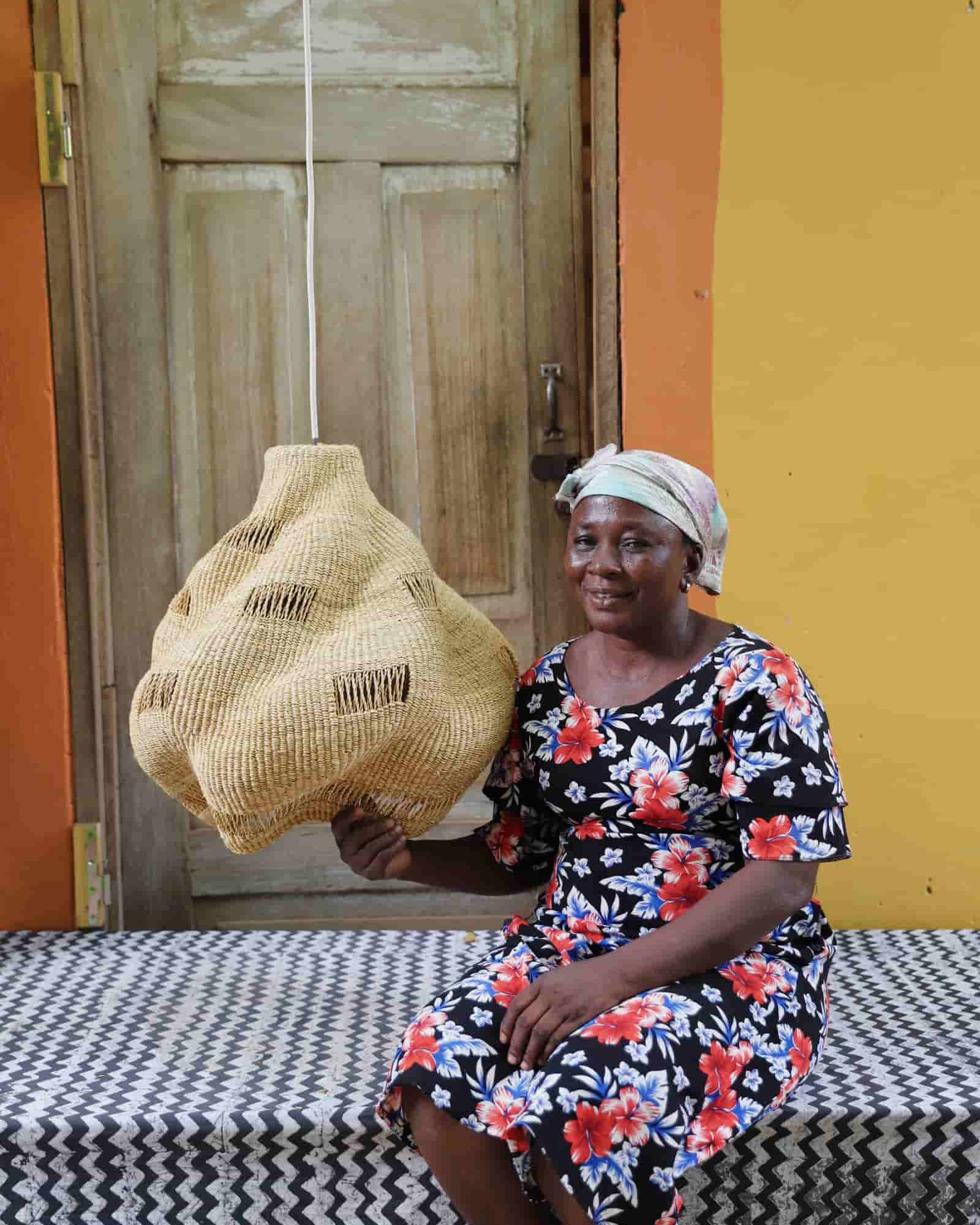 Woman holding a woven basket in front of a yellow wall and wooden door.