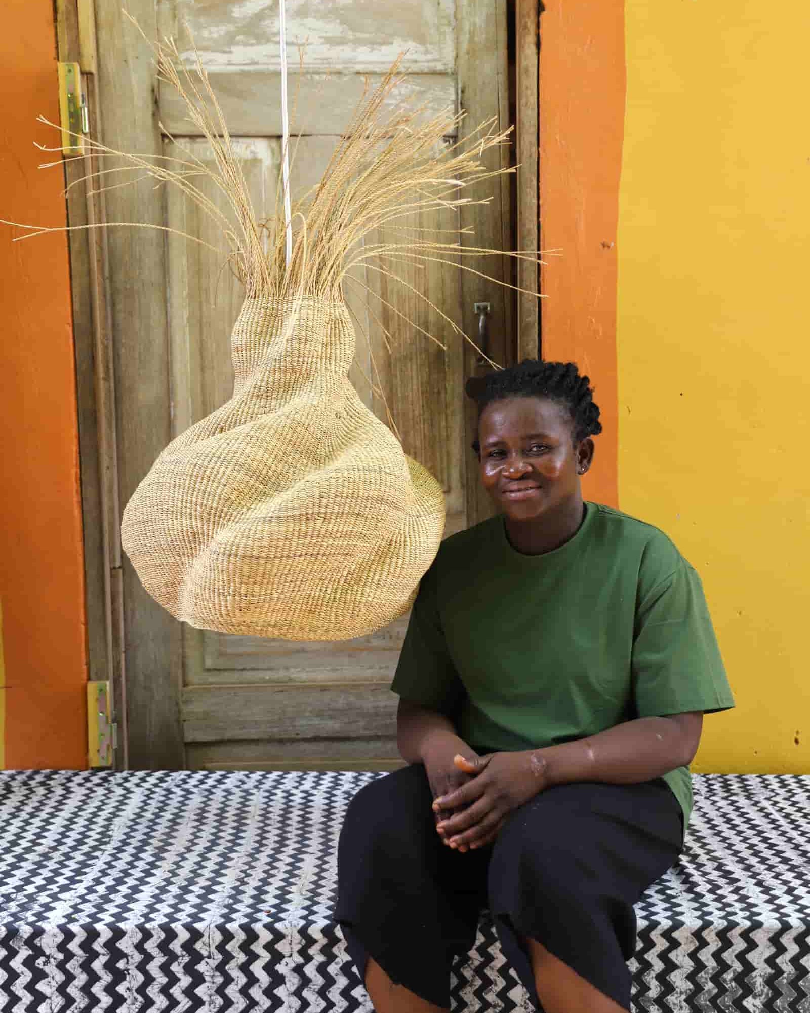 Person sitting on a bench with a large woven basket in front of a colorful wall.