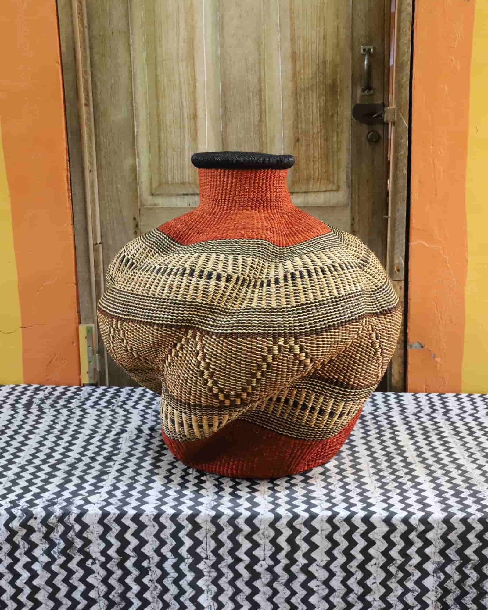 Large, colorful woven basket against a yellow wall.