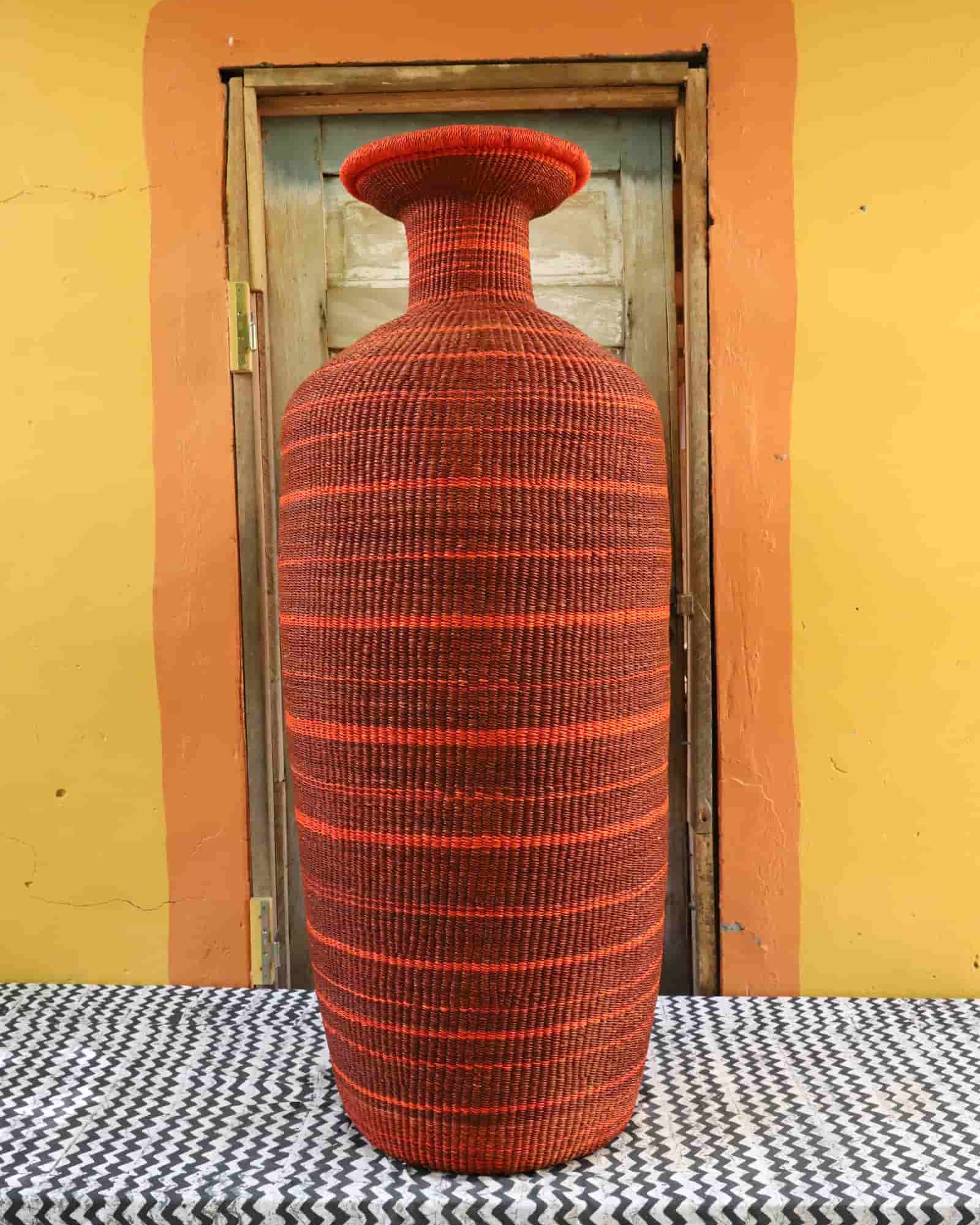 Red woven vase on a checkered tablecloth with a yellow wall and wooden door in the background
