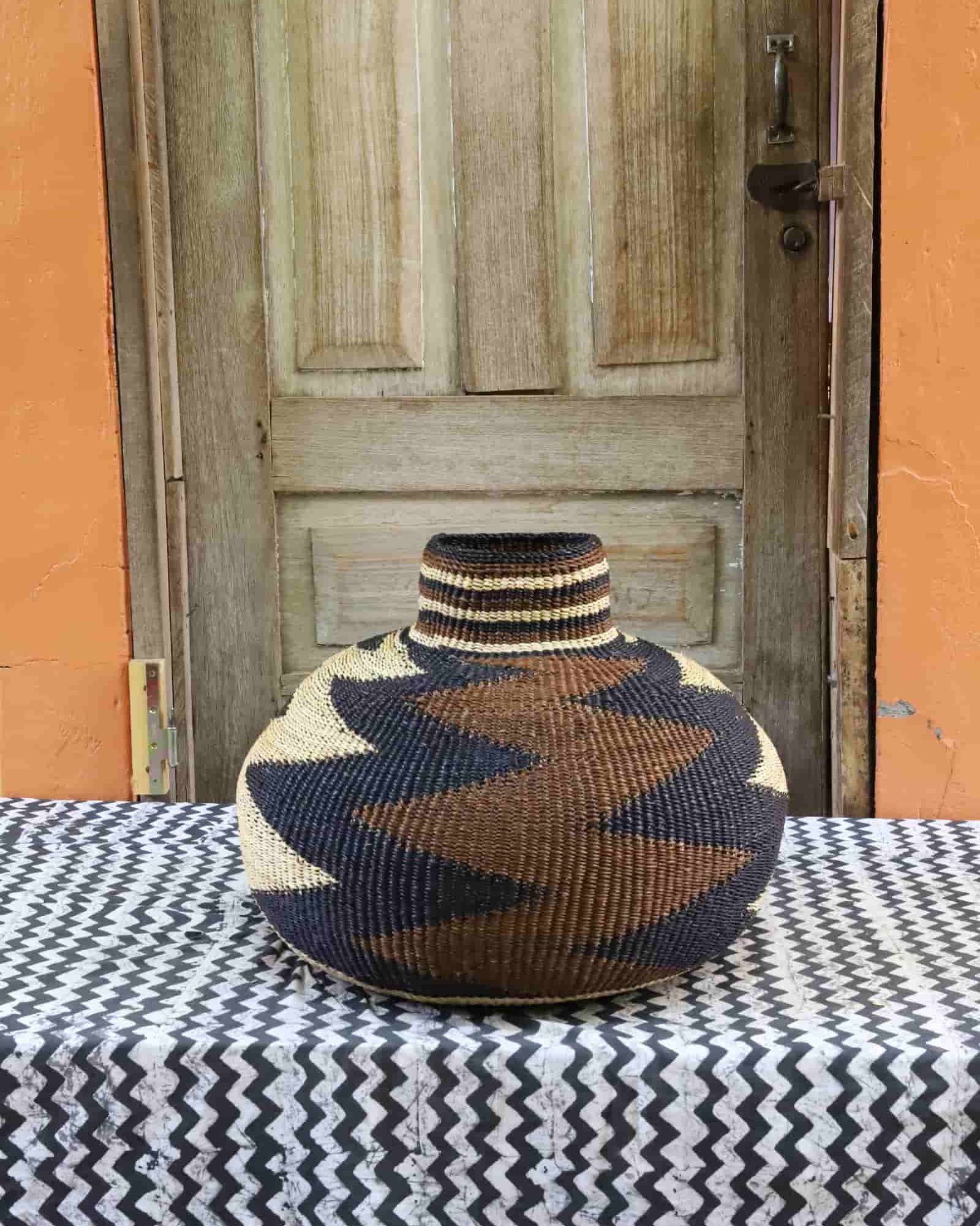 Woven décor with a beautiful pattern on a black and white cloth against a wooden door.