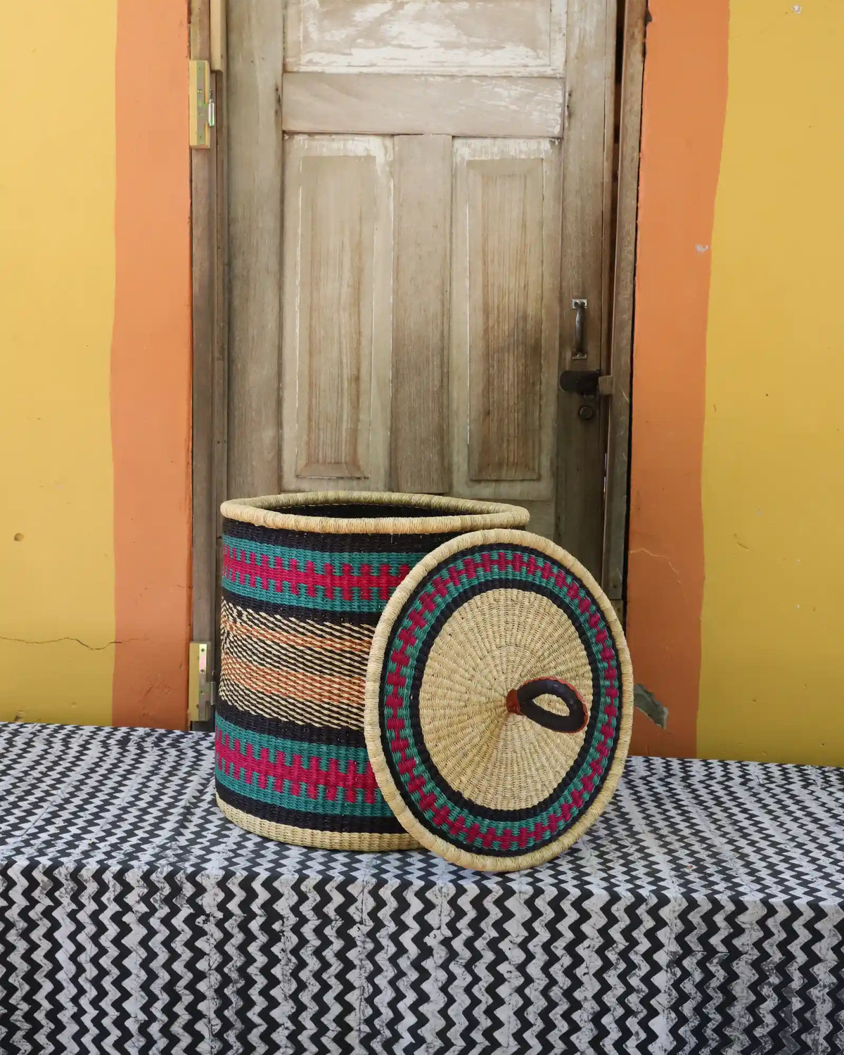 Handwoven Bolga laundry basket with lid removed, natural body with fine multicolour bands and coiled lid.