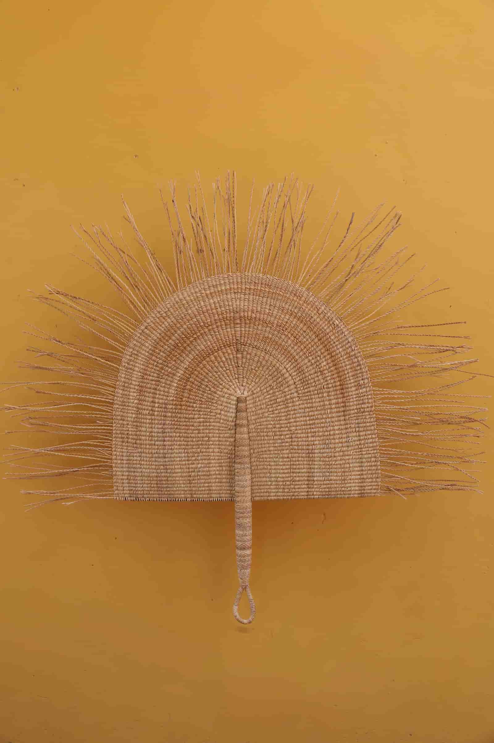 Decorative wall art with a sun design on a mustard yellow background