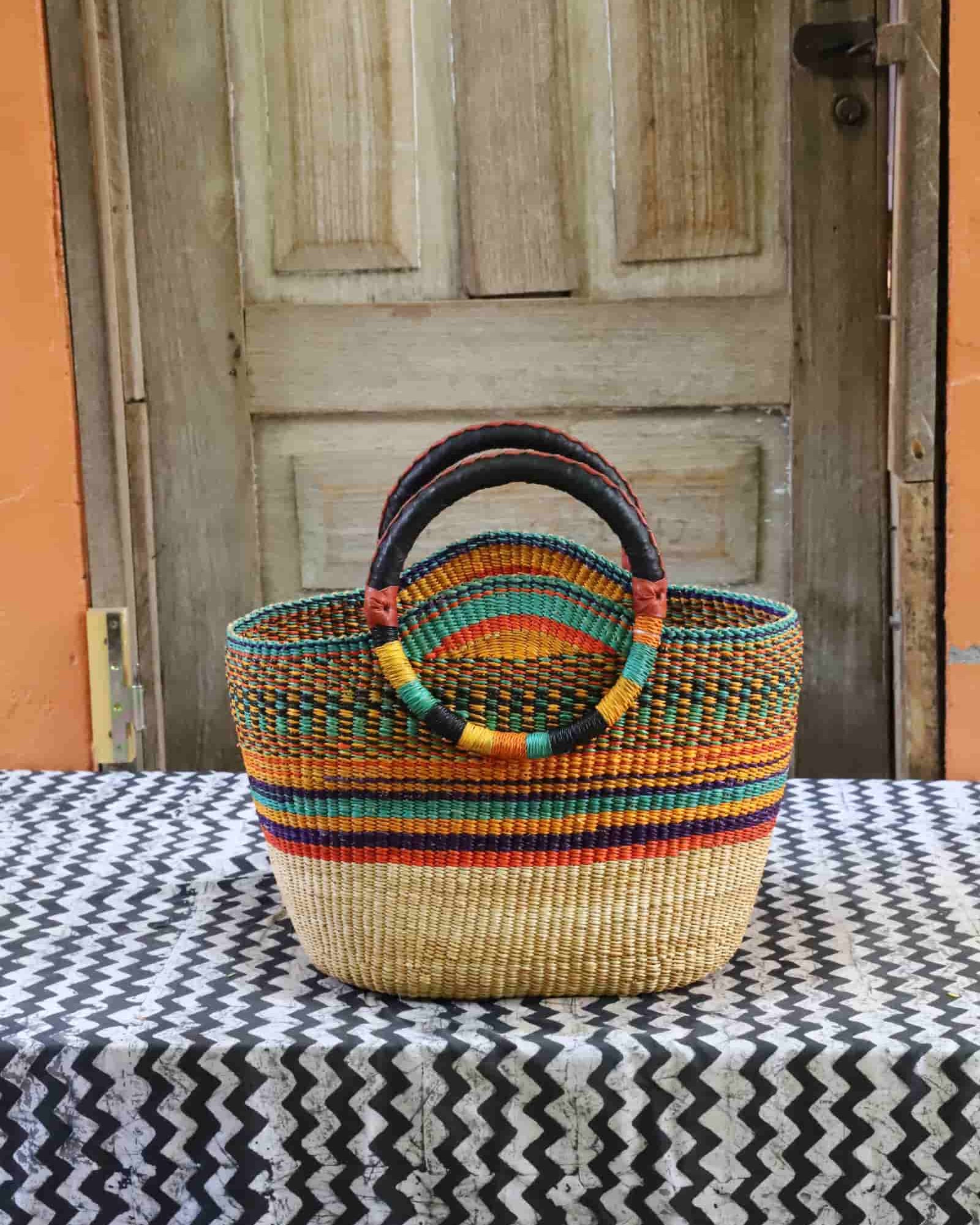 Colorful woven basket on a black and white patterned tablecloth with a wooden door in the background.