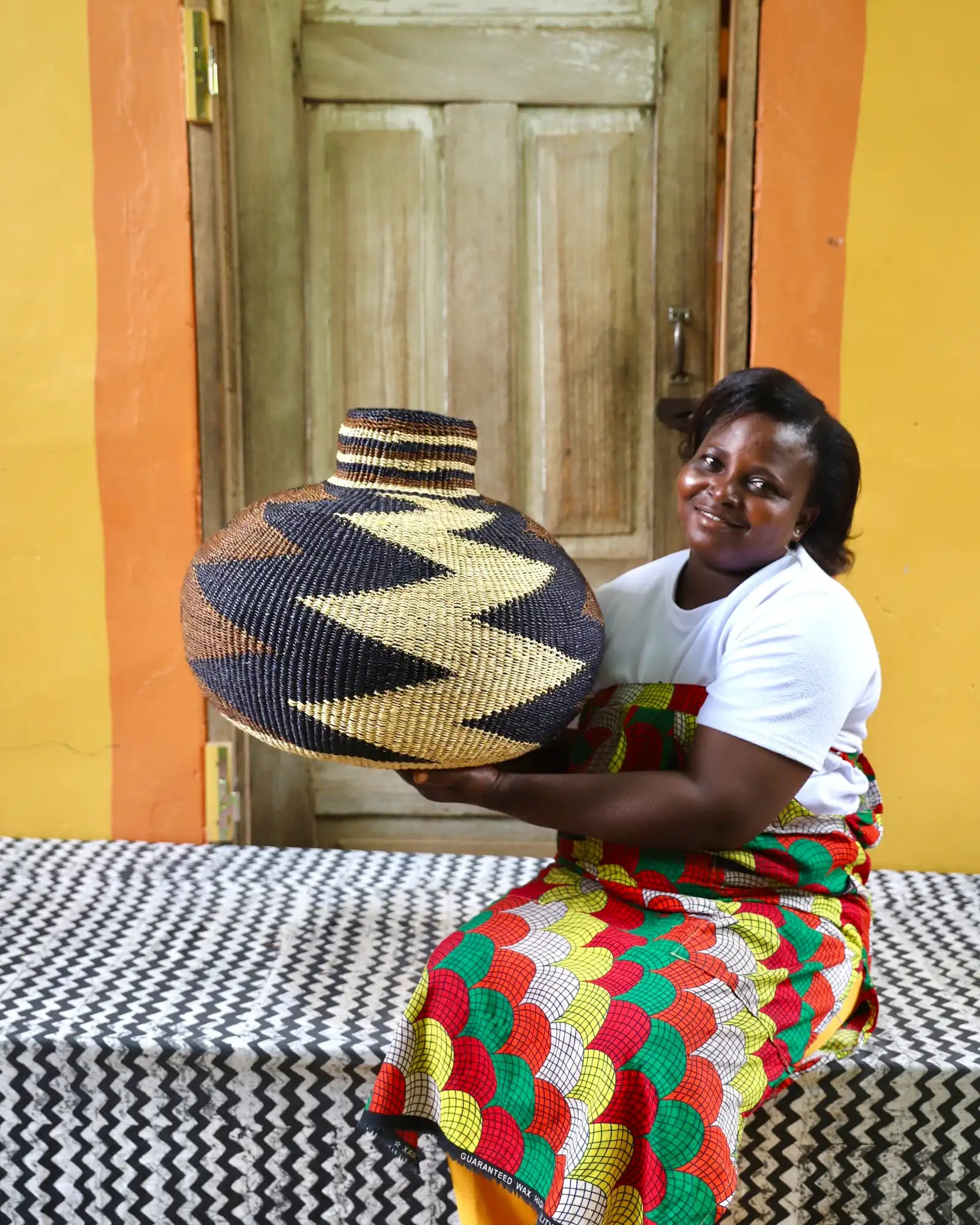 Woman holding a beautiful basket on a black and white cloth against a colorful background