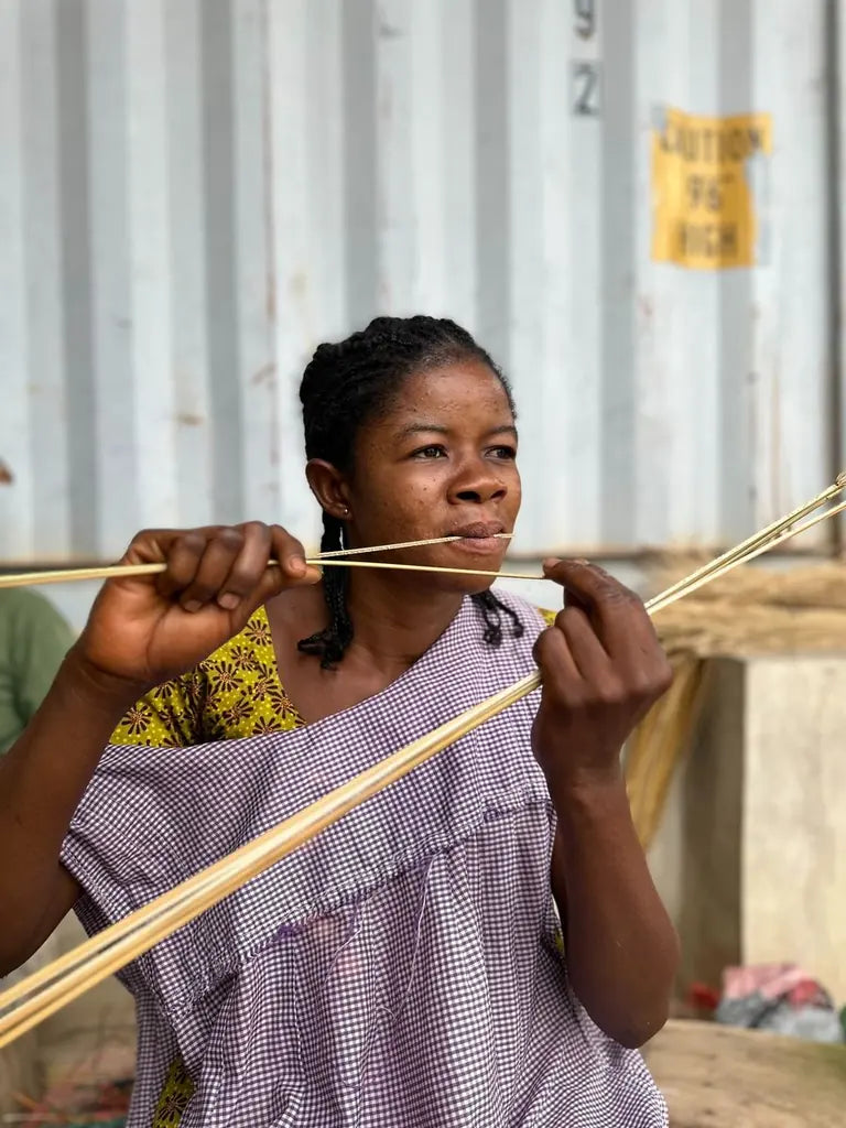 A basket maker splitting a strand of straw by hand