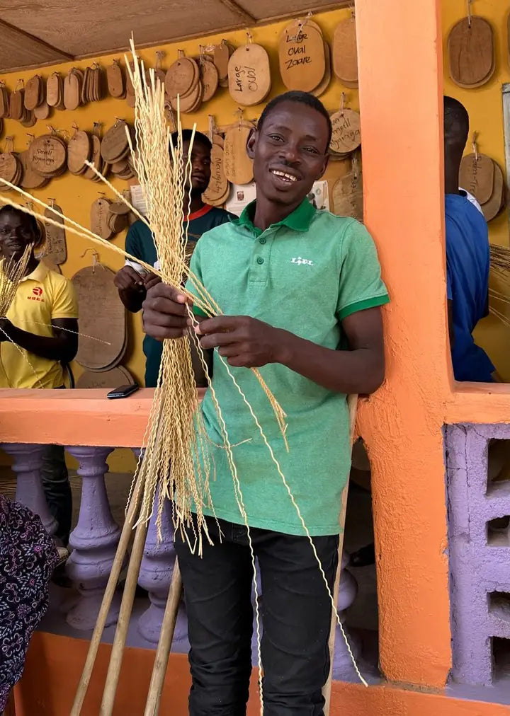 A basket maker holding long prepared strands of straw