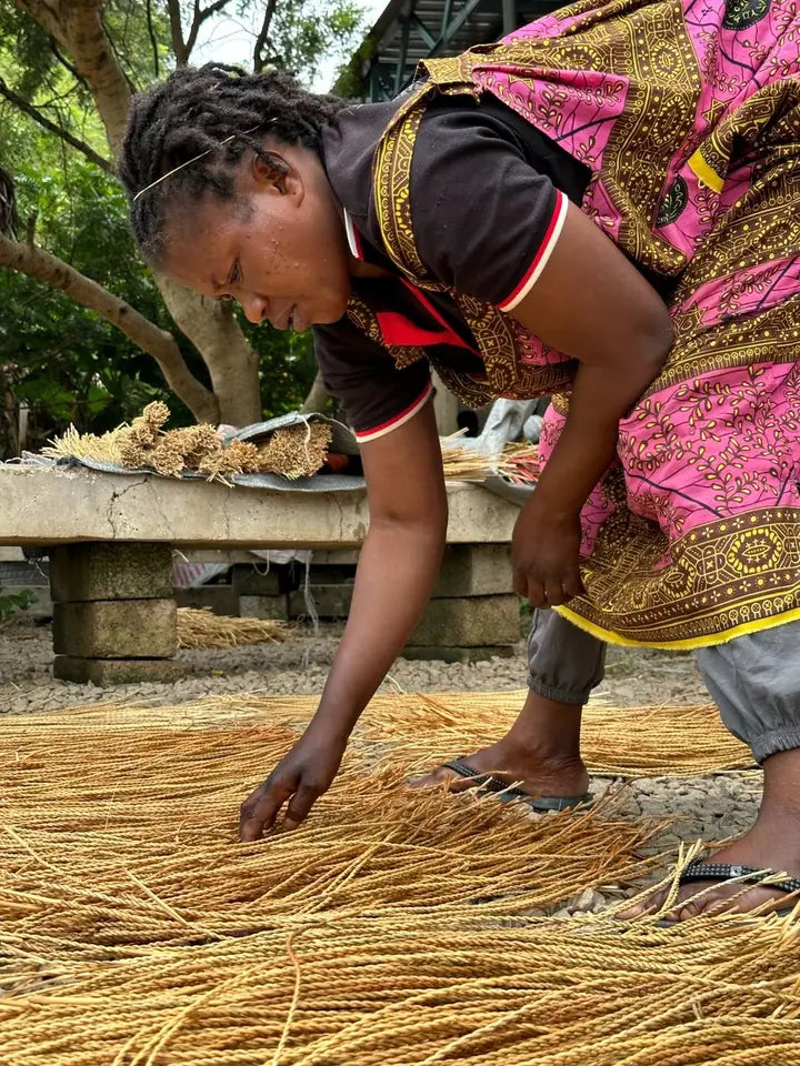 A basket maker arranging natural straw on the ground