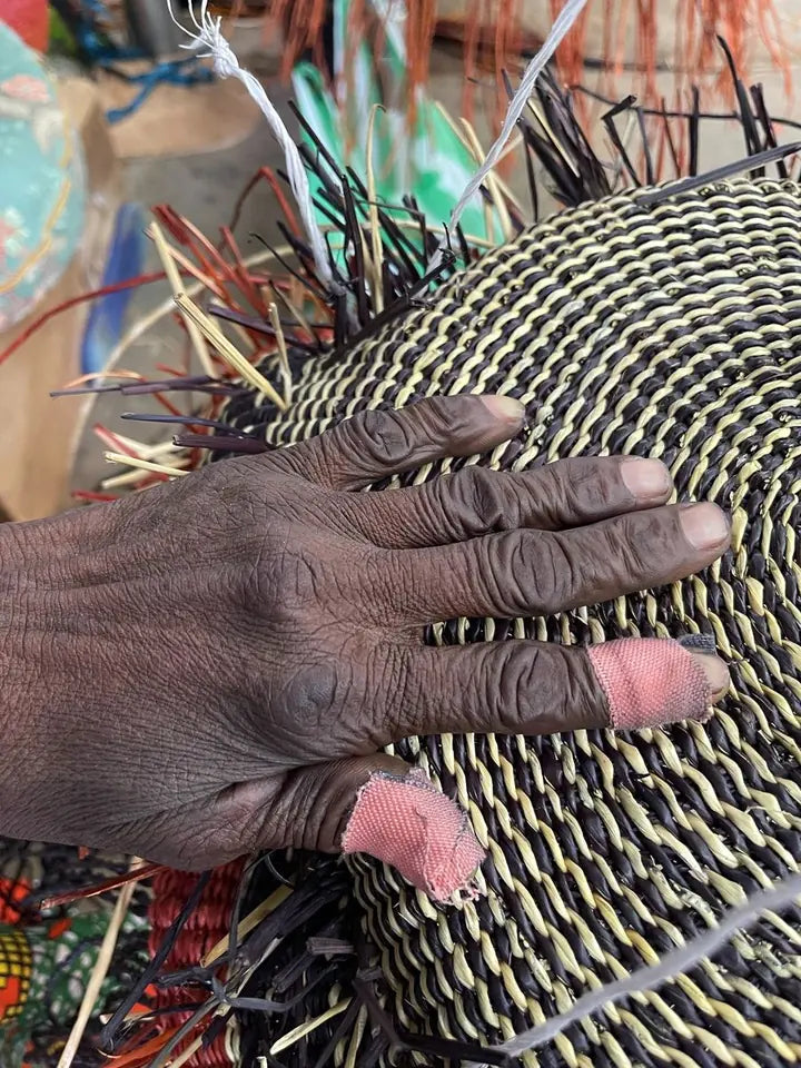 Hands weaving the circular base of a basket