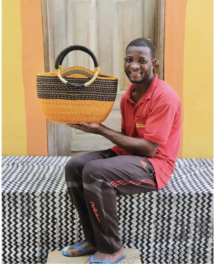A basket maker seated with a finished round market basket