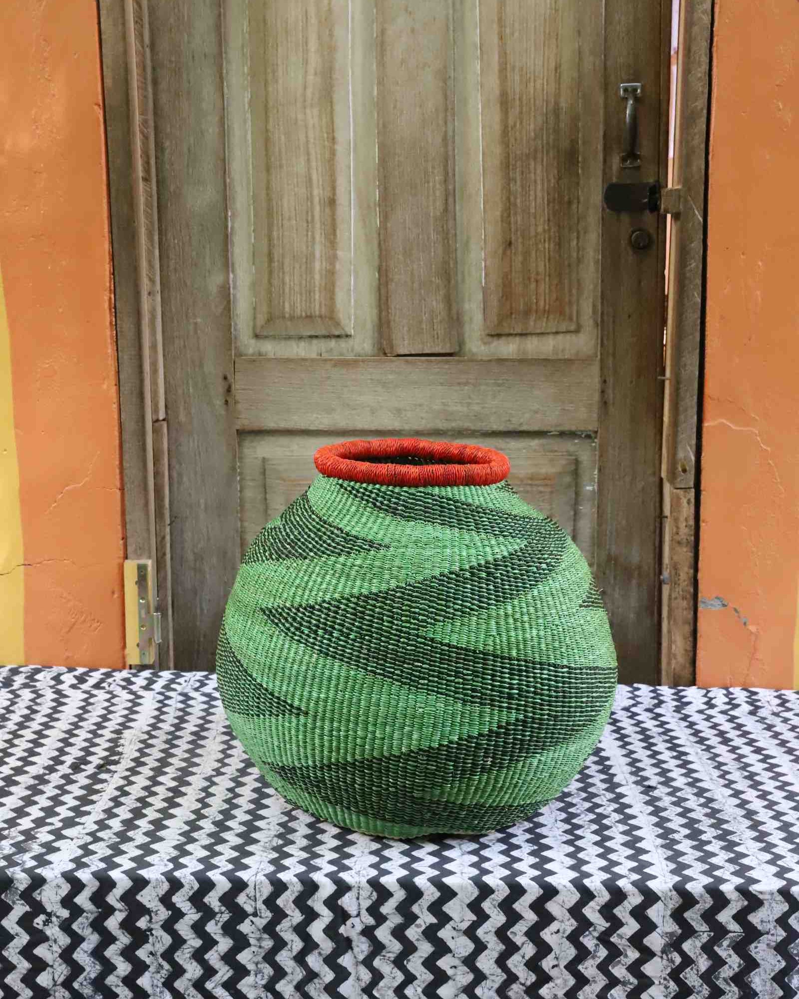 Round woven Bolga basket with striking geometric pattern in natural grasses