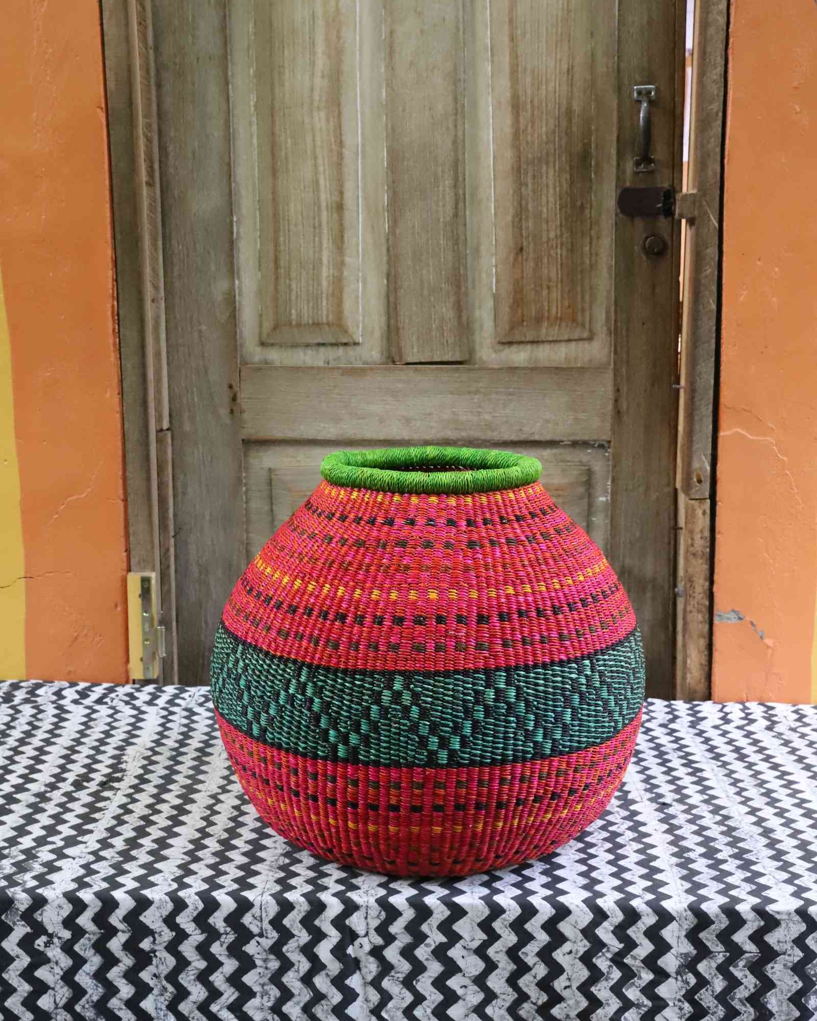 Round handwoven Bolga art basket with bold multi-coloured geometric pattern