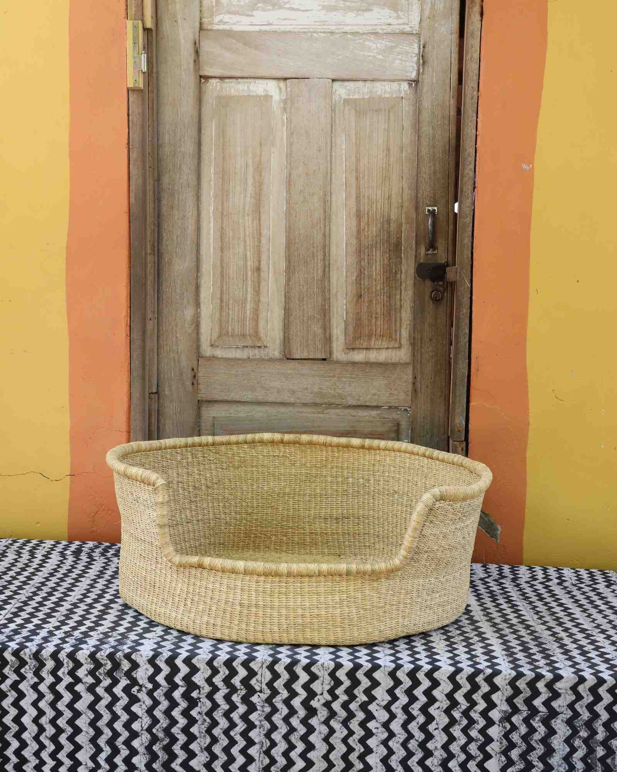 Large handwoven Bolga pet bed in plain natural straw with a fine dark rim detail.