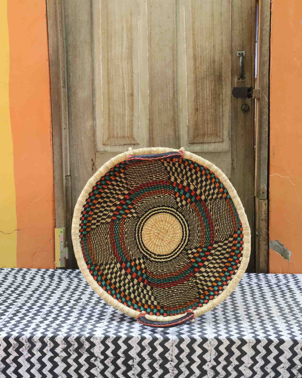 Handwoven Bolga wall tray disc in natural straw with fine dark concentric bands and radial dark rays.