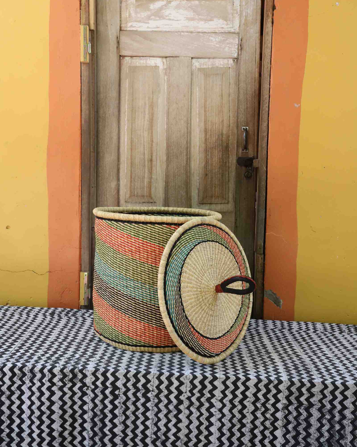 Handwoven Bolga laundry basket with lid removed, natural body with fine multicolour diagonal stripes.