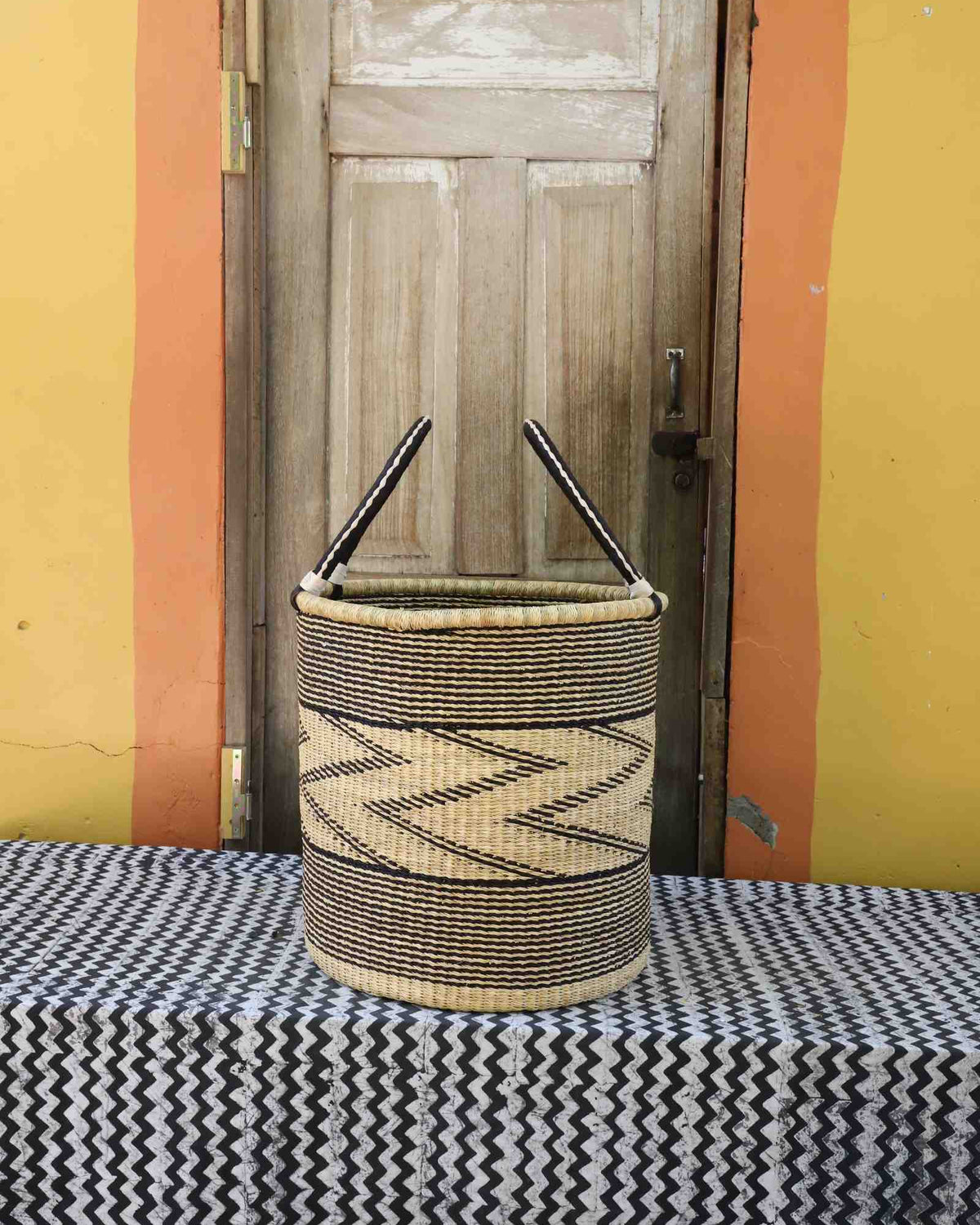 Large handwoven open-top Bolga laundry basket in natural straw with a fine black zigzag wave pattern.