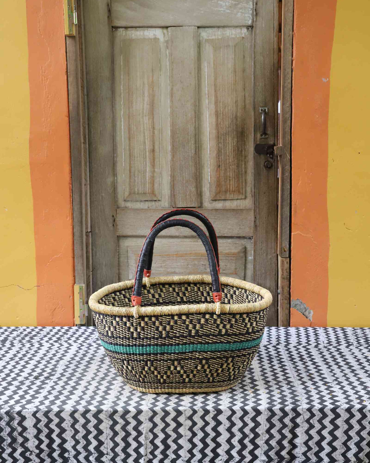Large handwoven oval Bolga shopping basket in natural straw with a teal and orange banded accent.