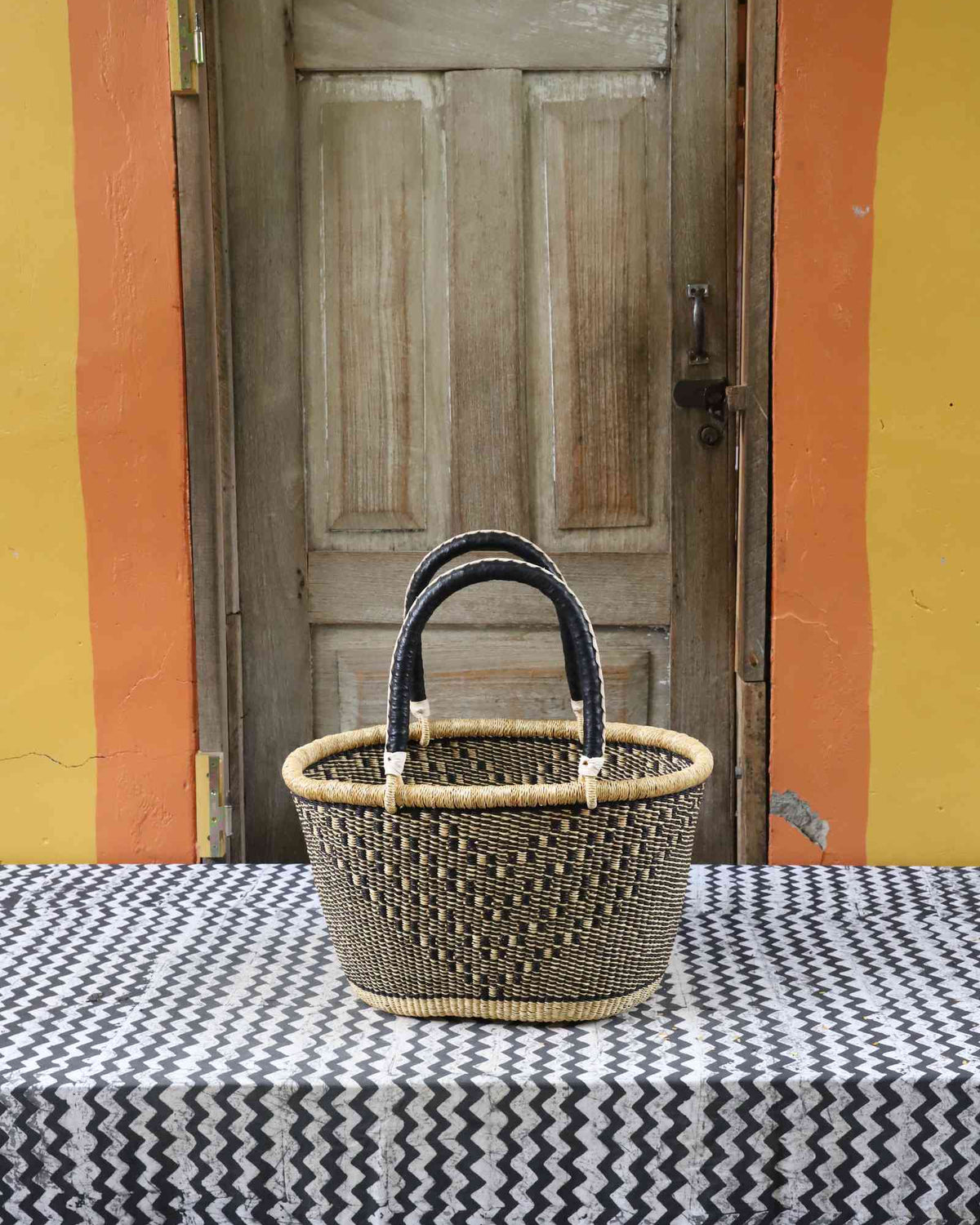 Large handwoven oval Bolga shopping basket in natural straw with a dark zigzag pattern and dark handles.
