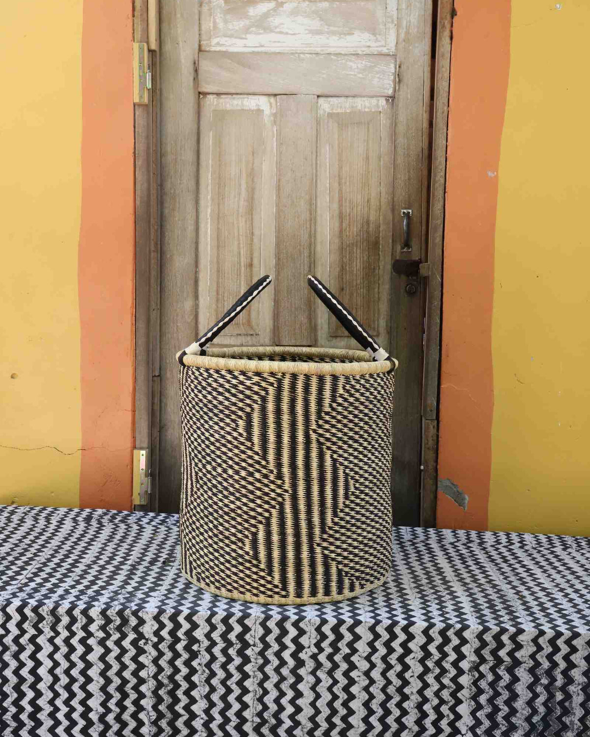 Large handwoven open-top Bolga laundry basket in natural straw with fine black diamond weave pattern.