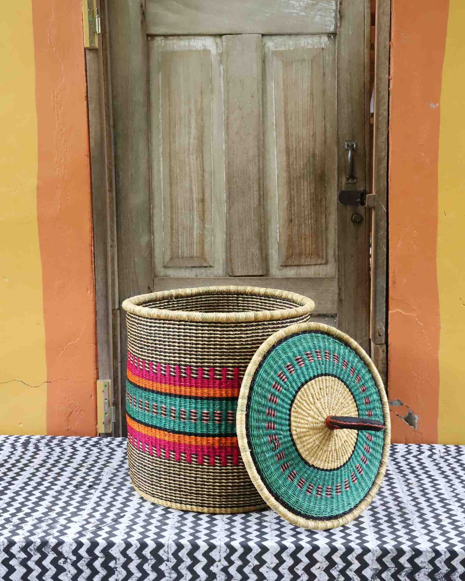 Handwoven Bolga laundry basket with lid removed, natural body with pink, orange, green and teal stripes.