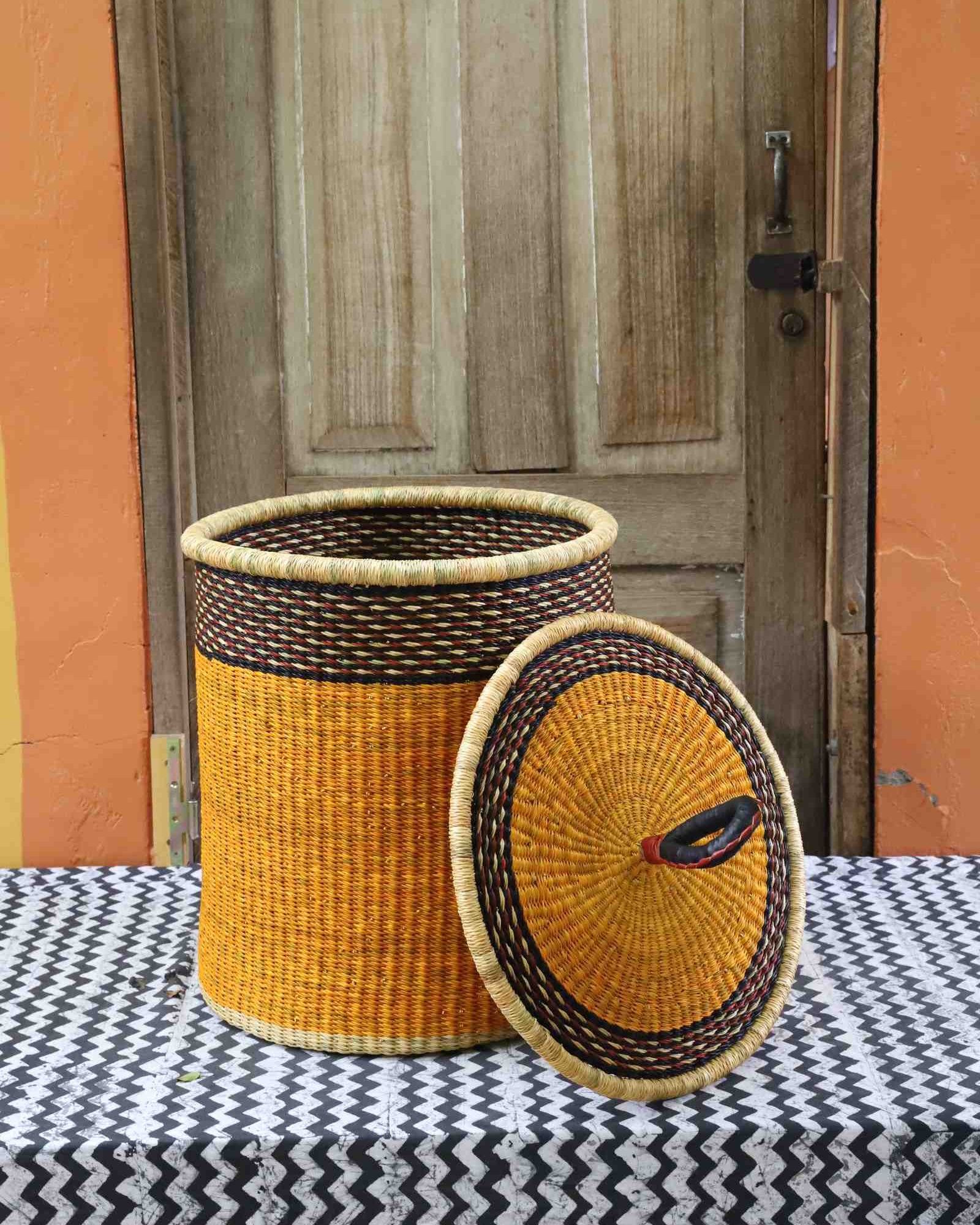 Coiled-rim laundry basket in solid mustard weave, lid resting alongside on a chevron cloth.