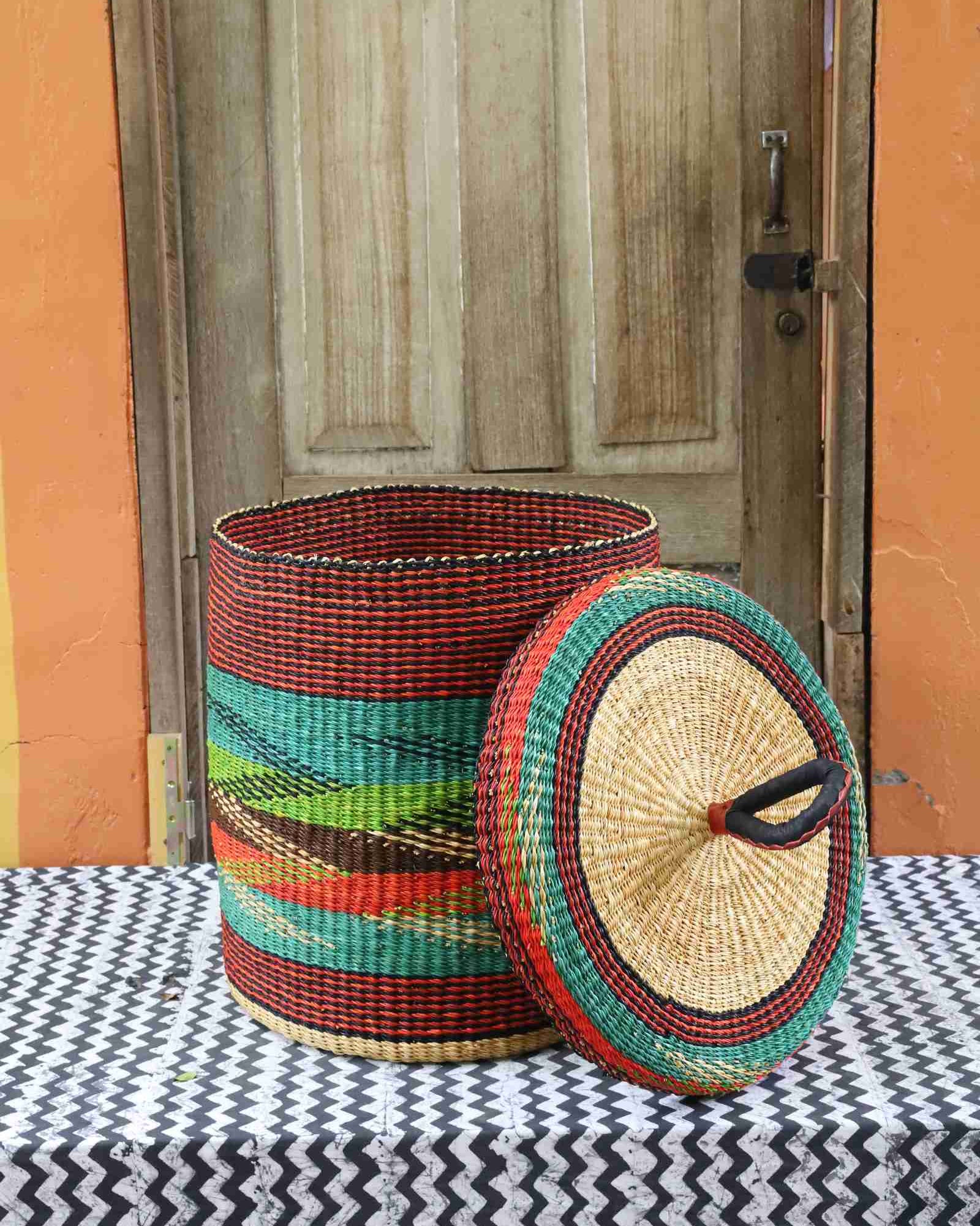Lidded laundry basket in rust and teal wave-patterned weave, lid resting alongside on a chevron cloth.
