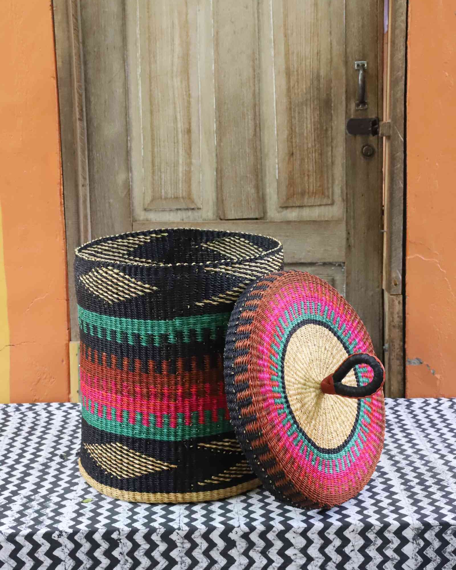 Lidded laundry basket in teal, pink and rust banded weave, lid resting alongside on a chevron cloth.