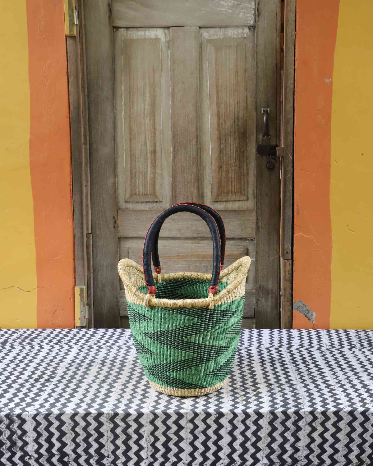 Medium handwoven Nyariga Bolga shopping basket in dyed green with a dark zigzag pattern and leather handles.
