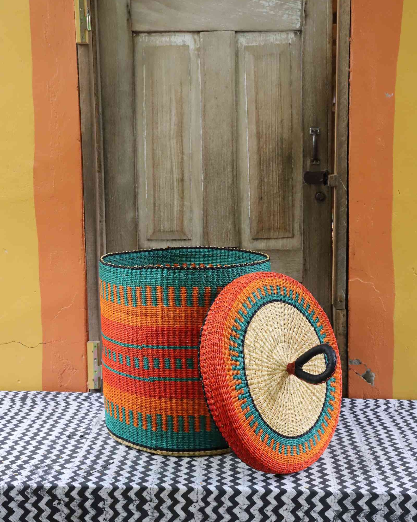 Handwoven Bolga laundry basket with lid removed, showing an orange and teal striped body and lid.